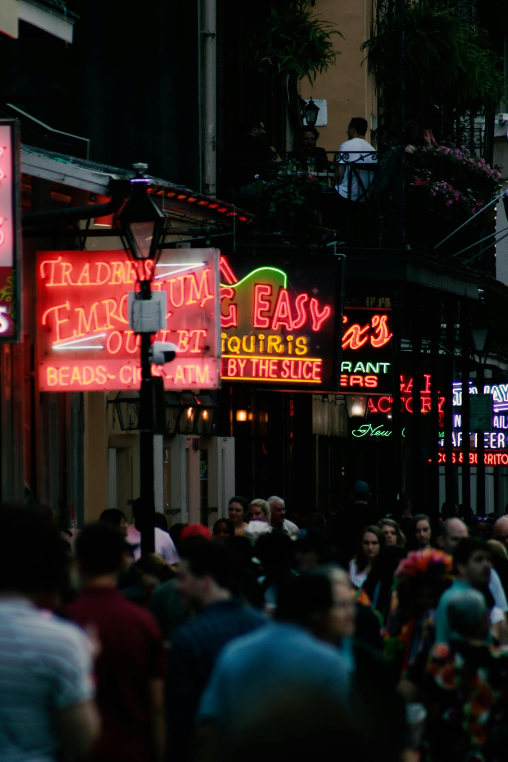 Lively Bourbon Street night in New Orleans, with glowing neon signs for bars and shops, and a bustling crowd.