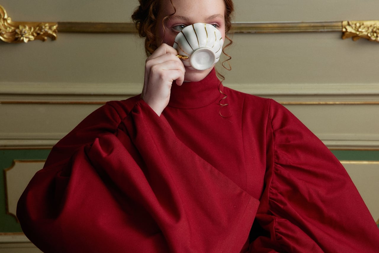 Elegant guest in red, sipping tea in a luxurious New Orleans historic suite.