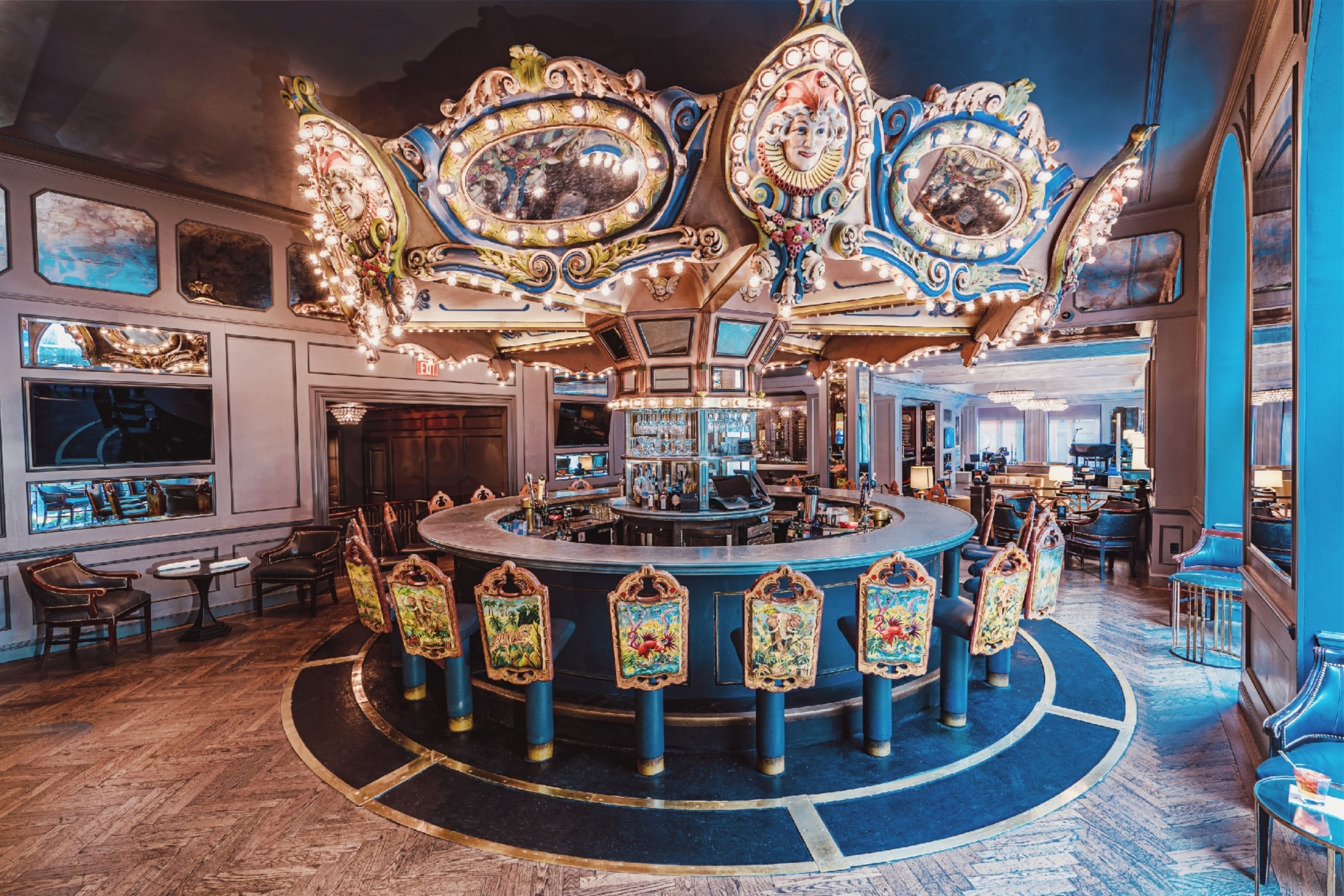 Ornate carousel bar with illuminated canopy and colorful stools in a luxury New Orleans hotel lounge.