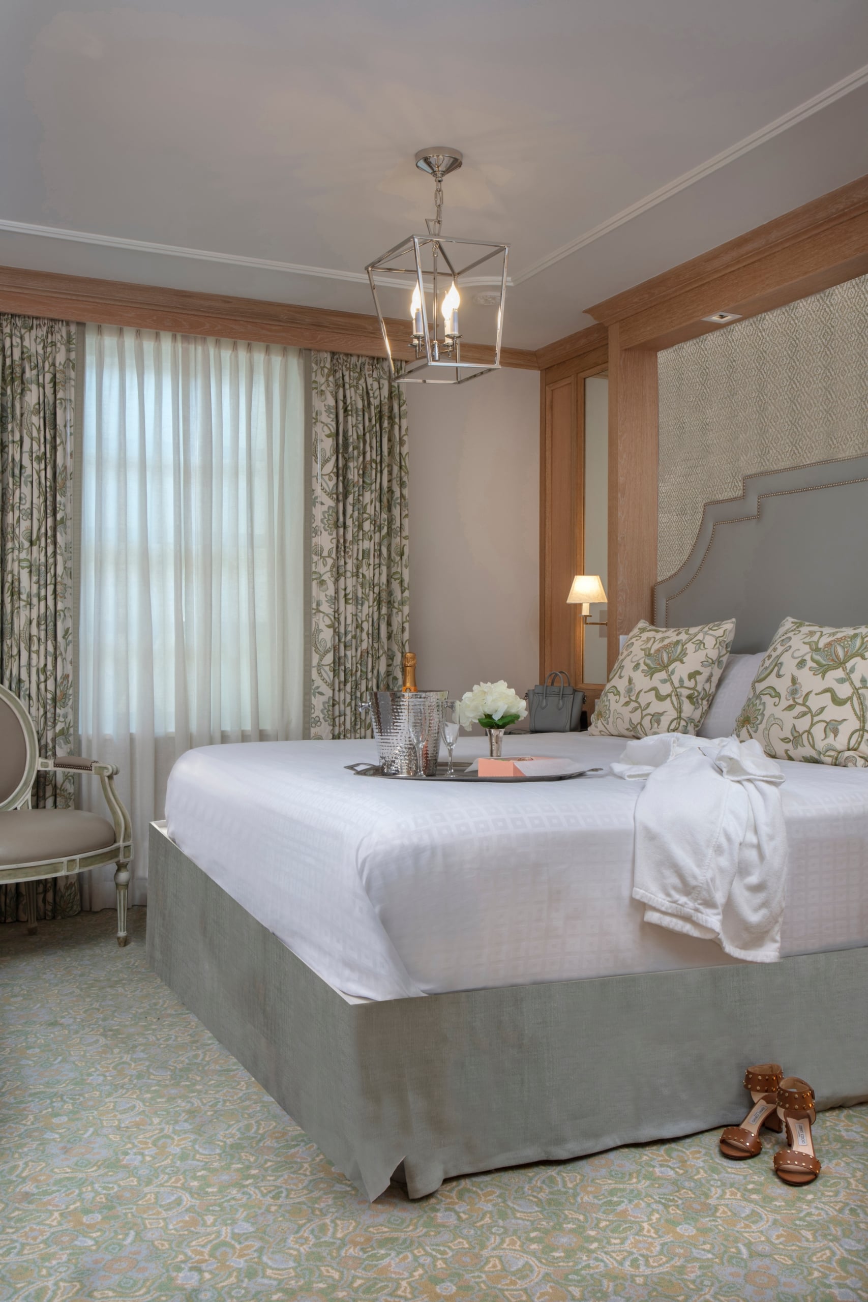 Elegant New Orleans hotel bedroom with a king bed, champagne service, white bathrobe, and floral decor.