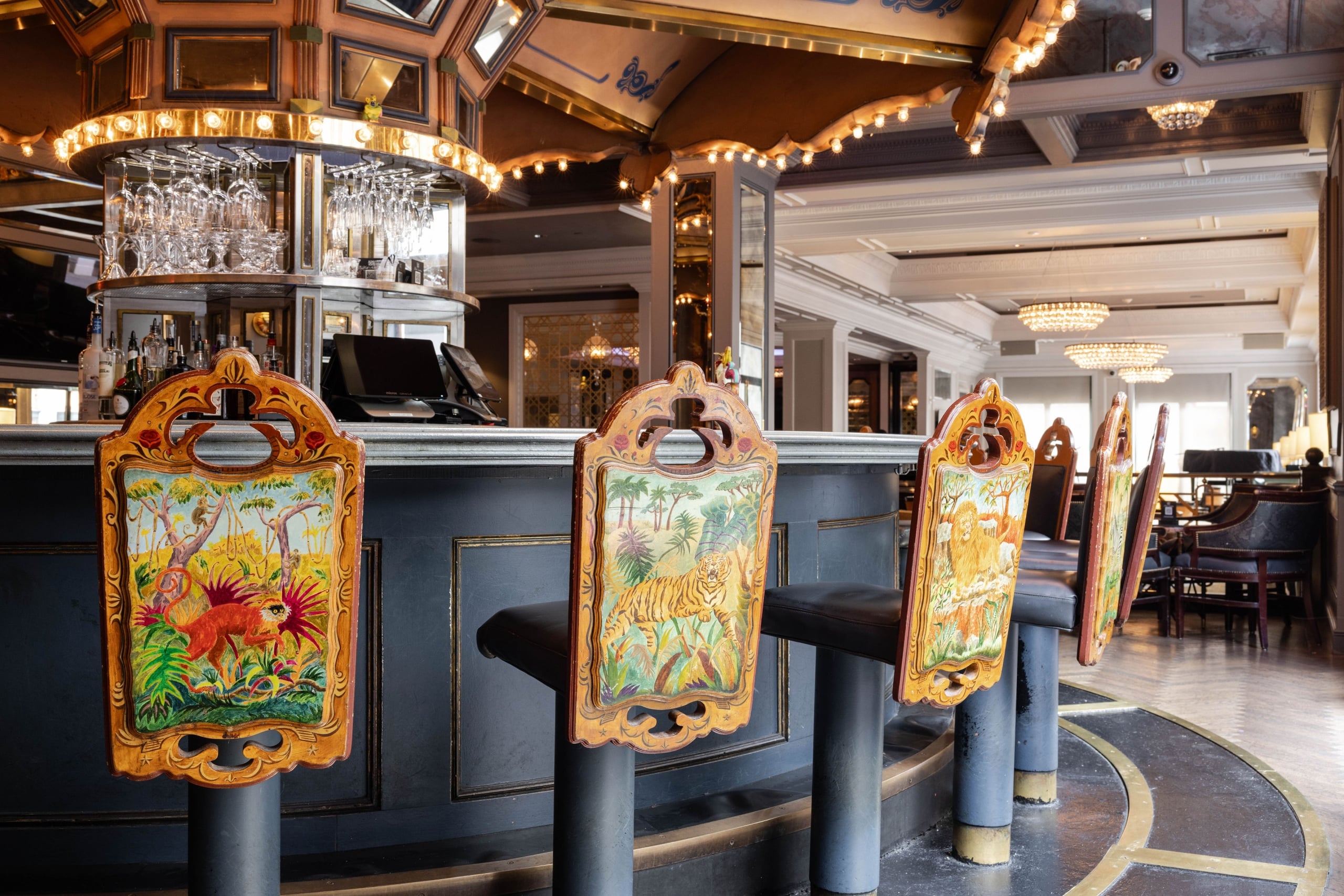 Luxurious New Orleans hotel bar with a vibrant carousel design and safari themed bar stools.
