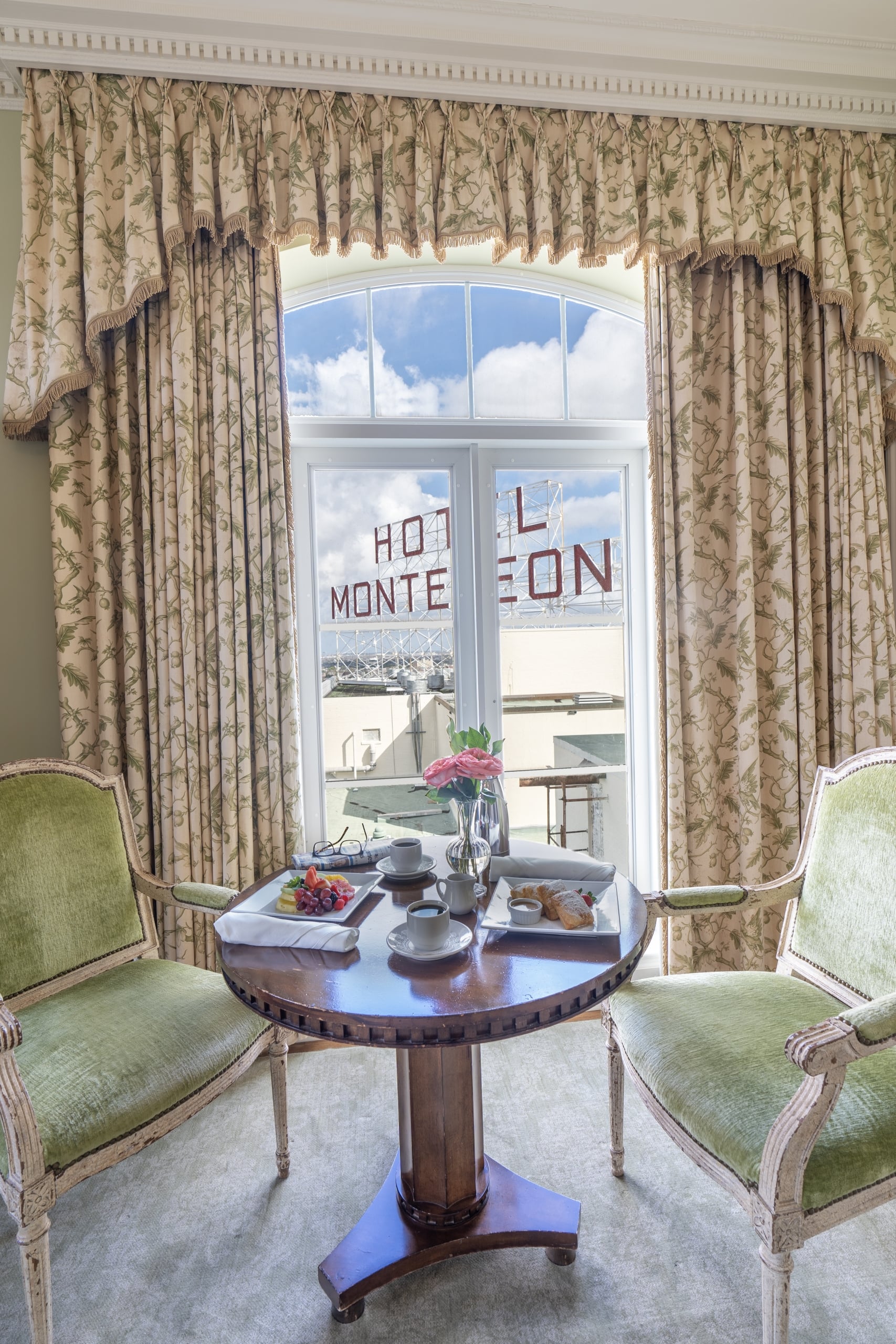 Luxurious Hotel Monteleone room in New Orleans with breakfast, beignets, elegant green chairs, and hotel sign view.