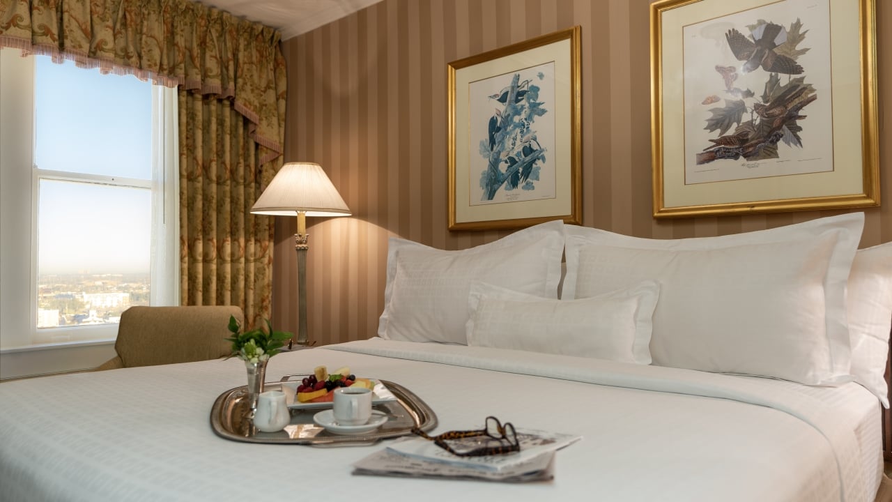 a hotel room with a bed, lamp, and window