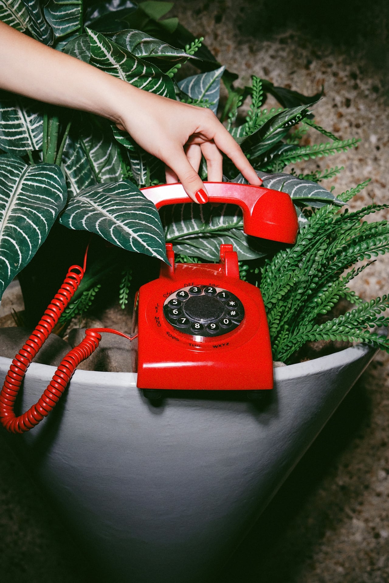 Vibrant red vintage rotary phone with a hand lifting the receiver, inviting unique New Orleans stays.