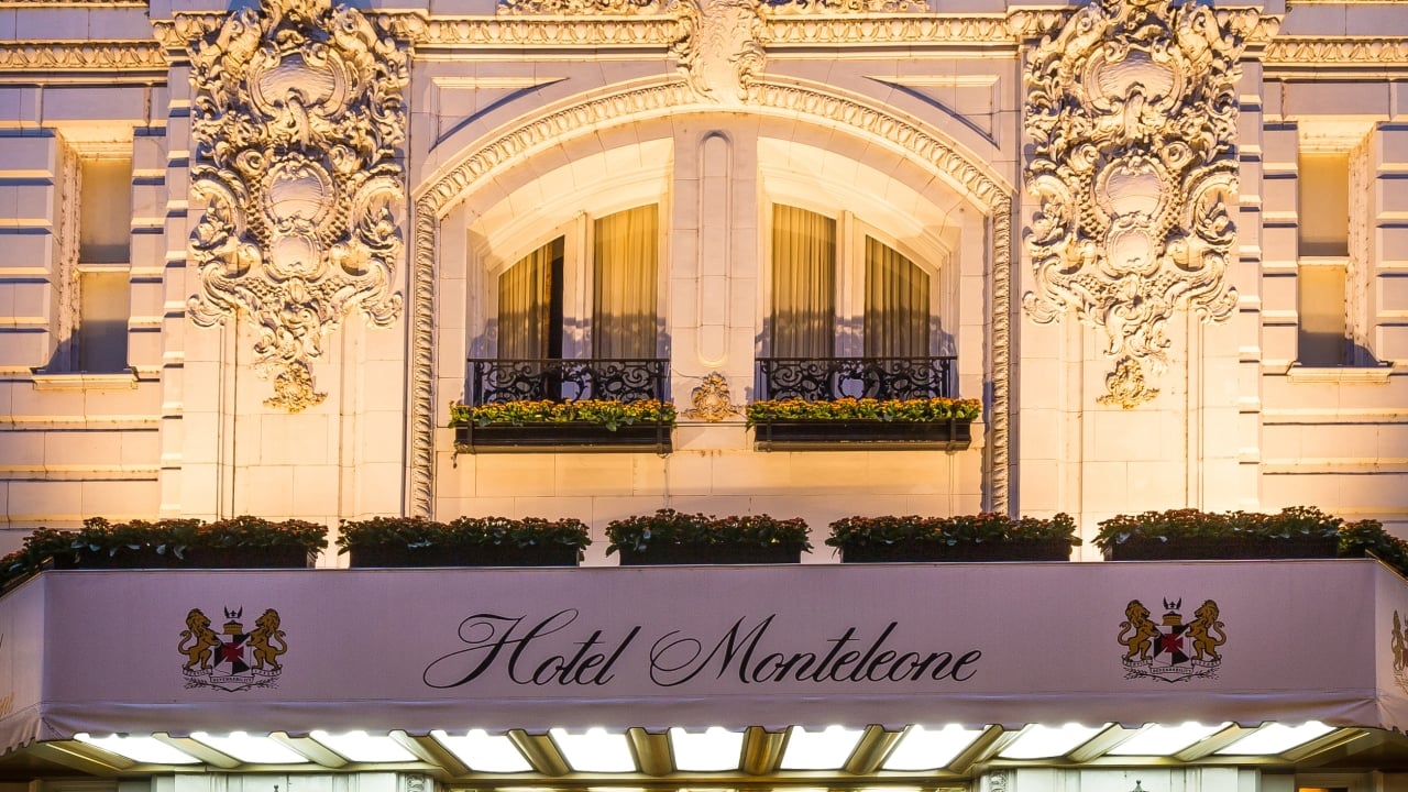 The ornate facade of a hotel with a balcony and awning that reads 'Hotel Monteleone'