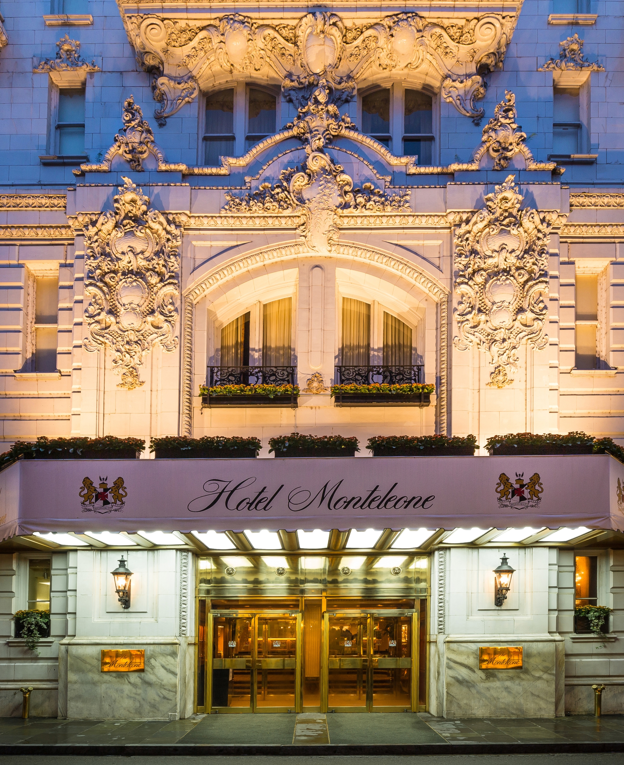 Hotel Monteleone entrance at night, featuring ornate architecture, a lit awning, and brass doors in New Orleans.