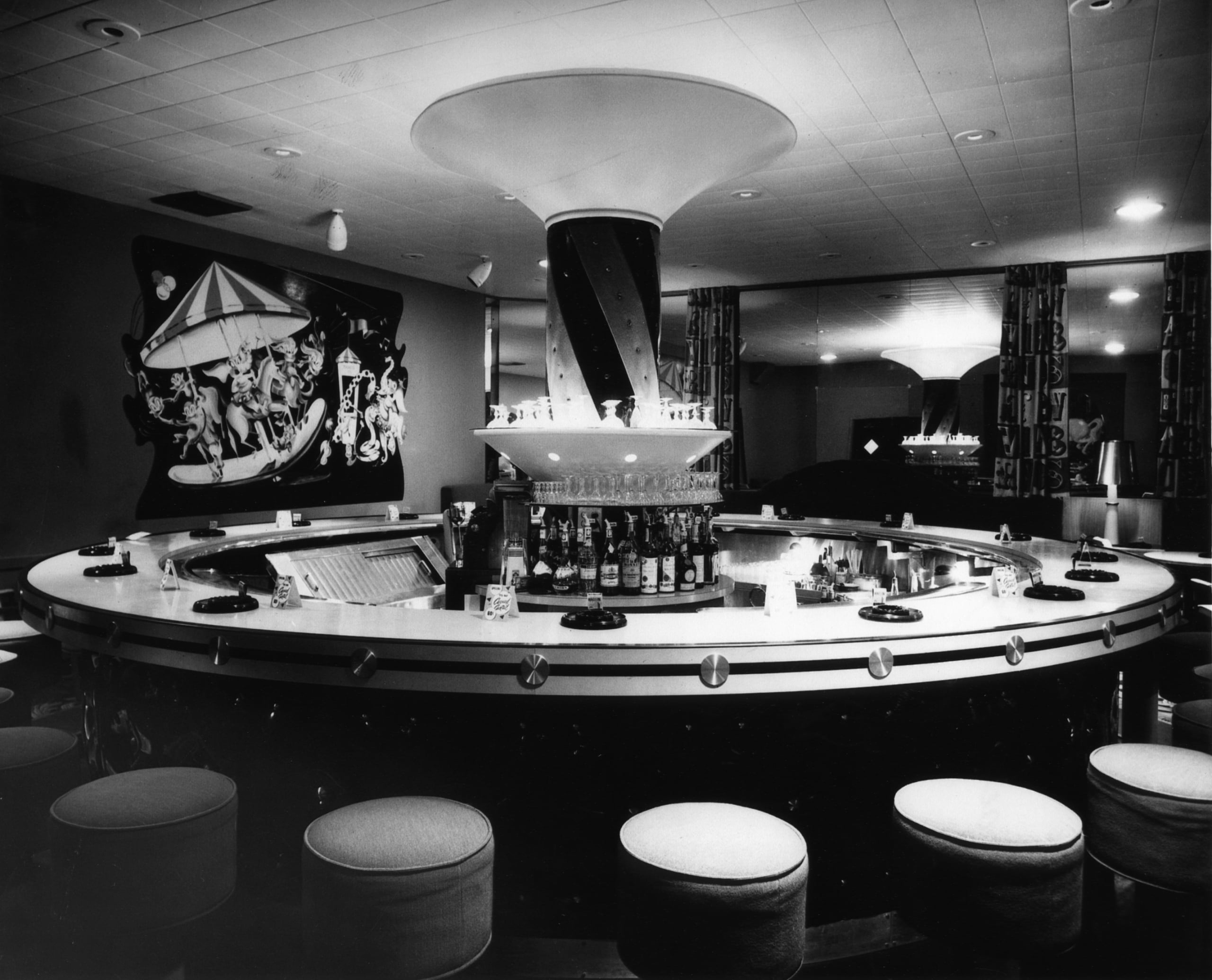 Vintage circular bar with central pillar, carousel mural, and bar stools.