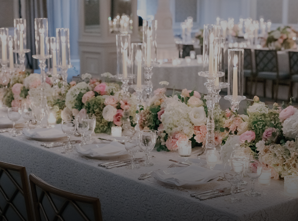 A long dining table set with flowers, candles, and fine china.