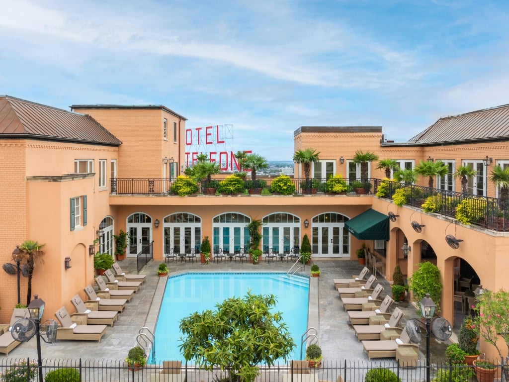 A hotel exterior with a pool and lounge chairs