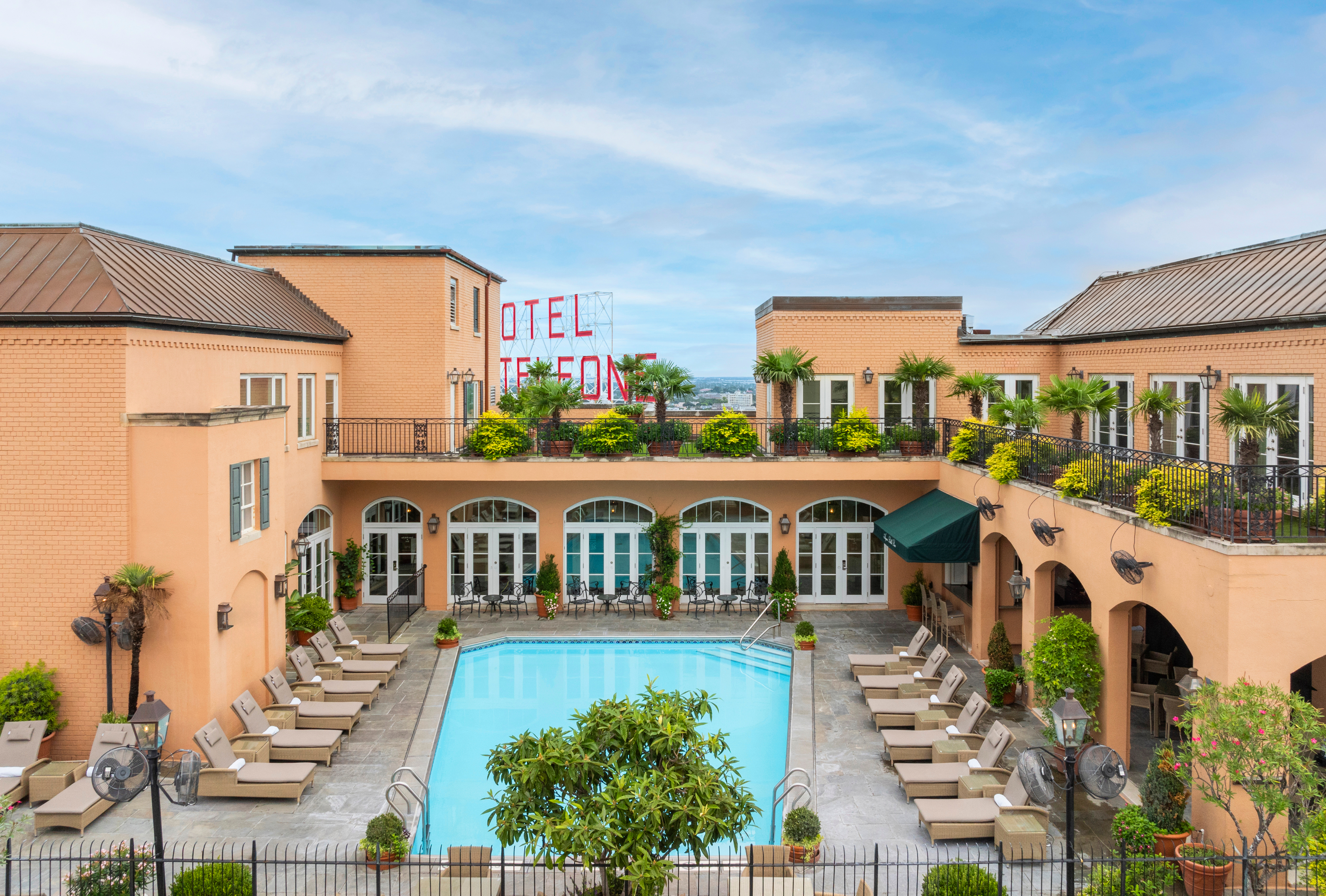 A hotel exterior with a pool and lounge chairs