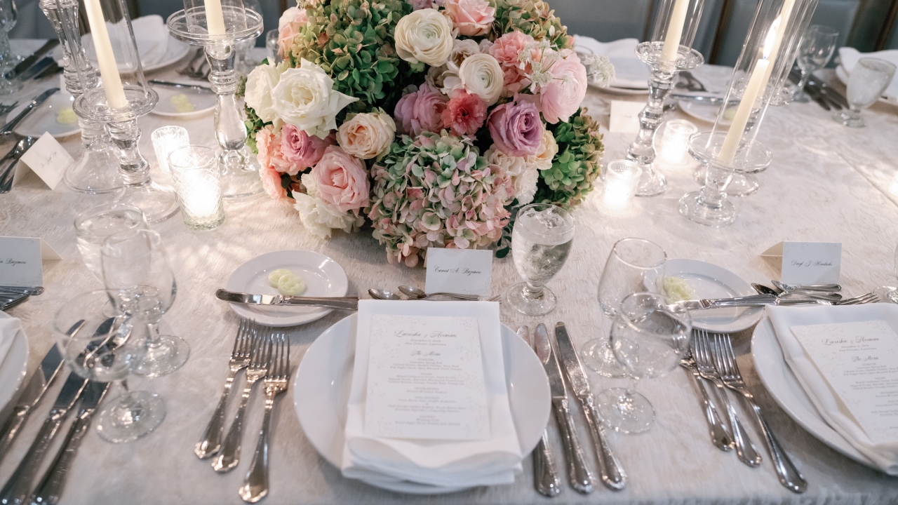 A formal dining table set with flowers, candles, and place settings.