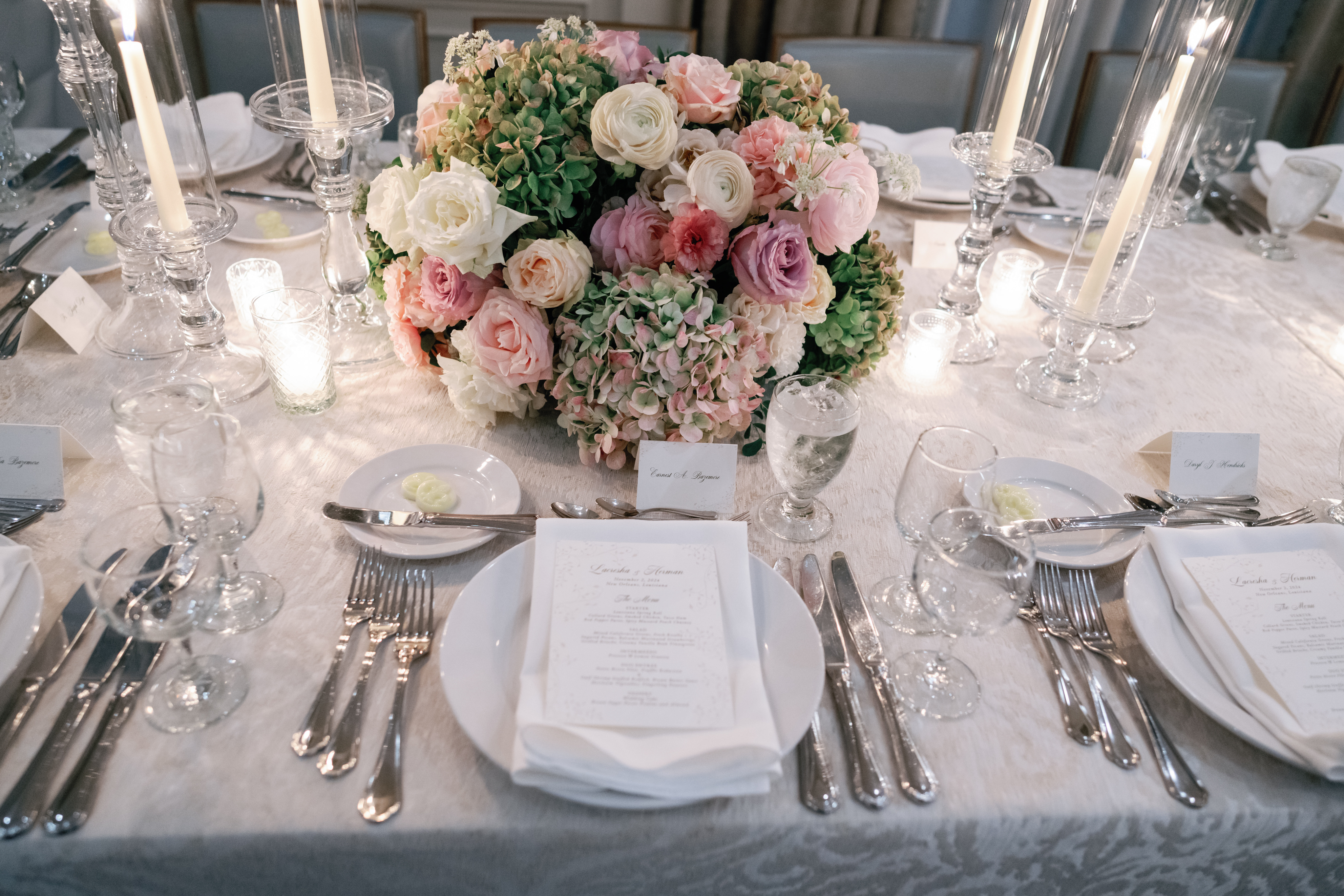 A formal dining table set with flowers, candles, and place settings.