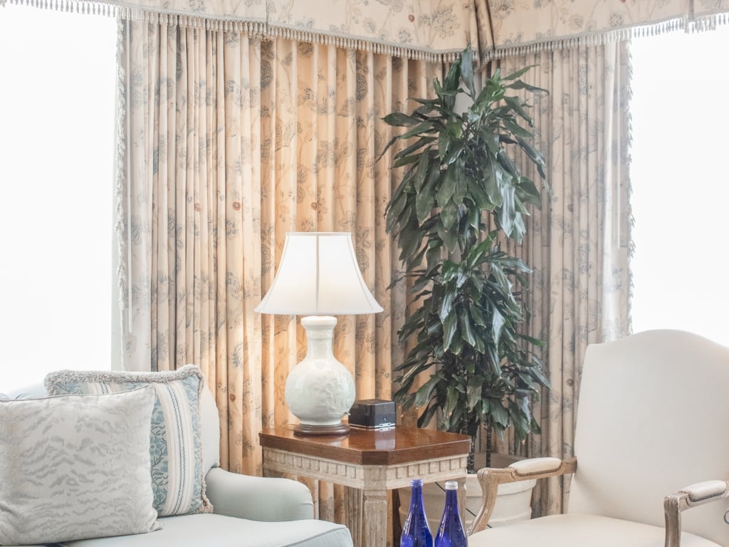 A cozy lounge area with a lamp, chair, sofa, and plant.