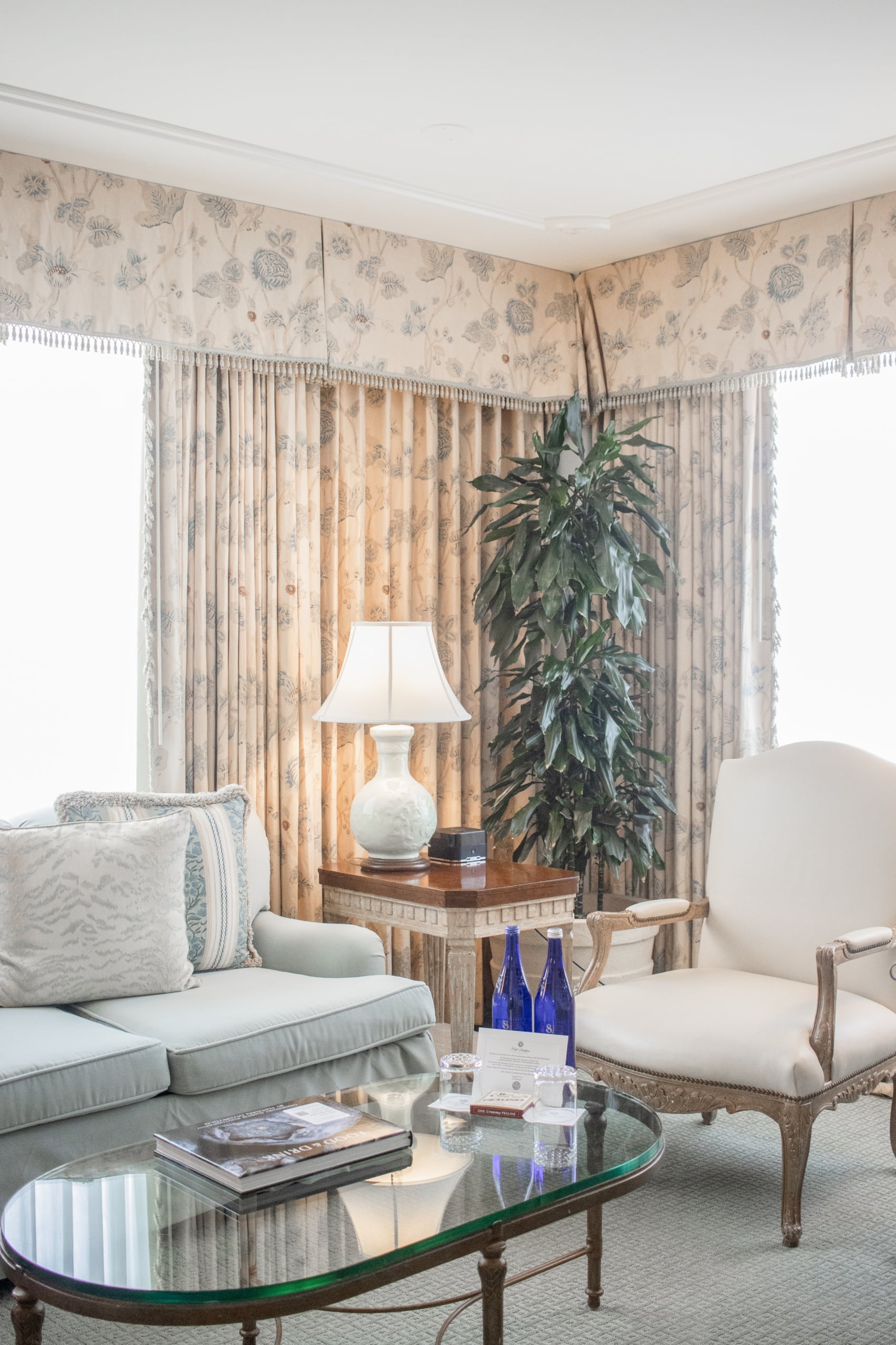 Luxurious hotel suite lounge in New Orleans with elegant furniture, floral drapes, and local pralines on the table.
