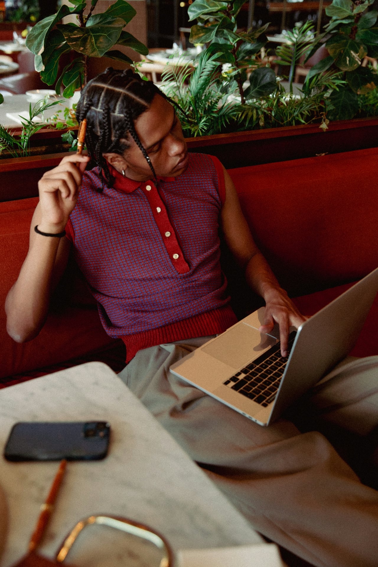Traveler with braided hair using laptop on a red sofa in a New Orleans lounge.