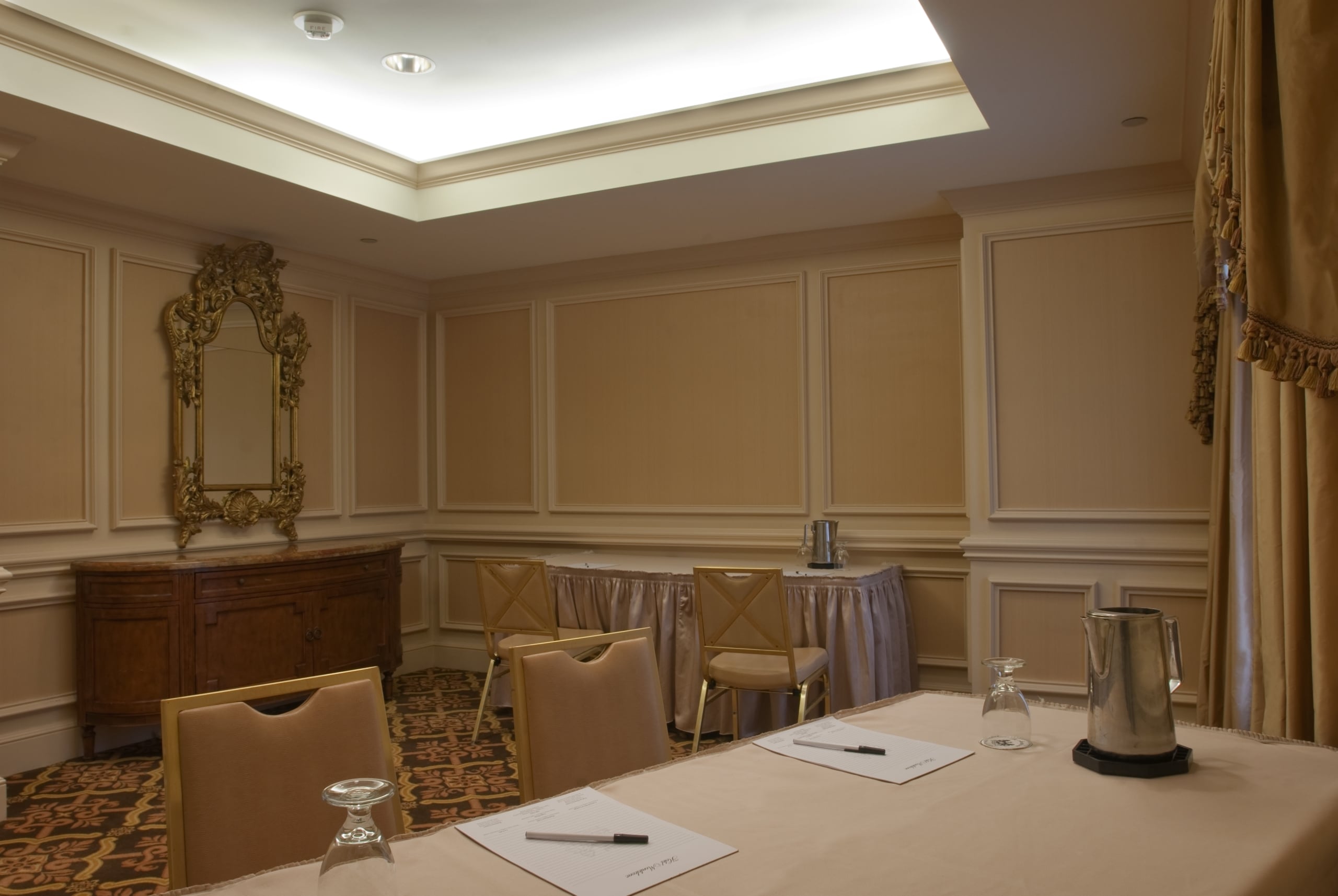 Elegant meeting room at Hotel Monteleone New Orleans, with a conference table, chairs, and ornate gold mirror.