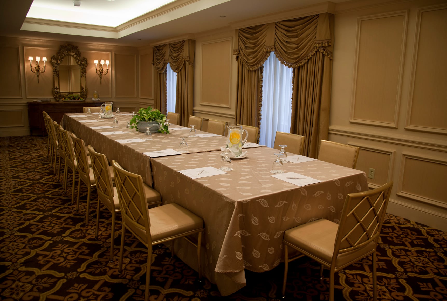 Elegant New Orleans meeting room with a long table, gold chairs, and ornate decor, ready for events.