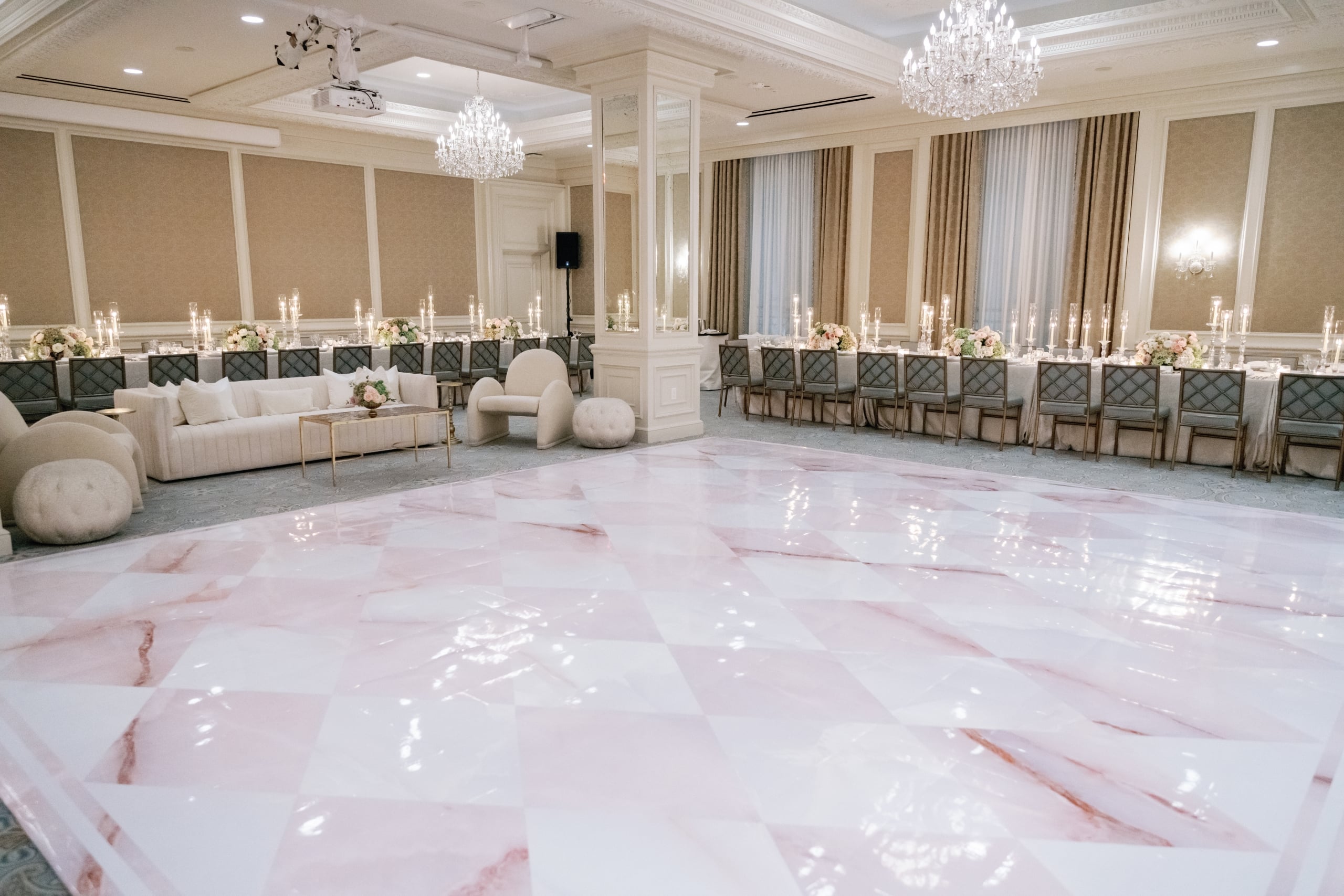 Elegant New Orleans ballroom with a pink and white dance floor and beautifully decorated dining tables.