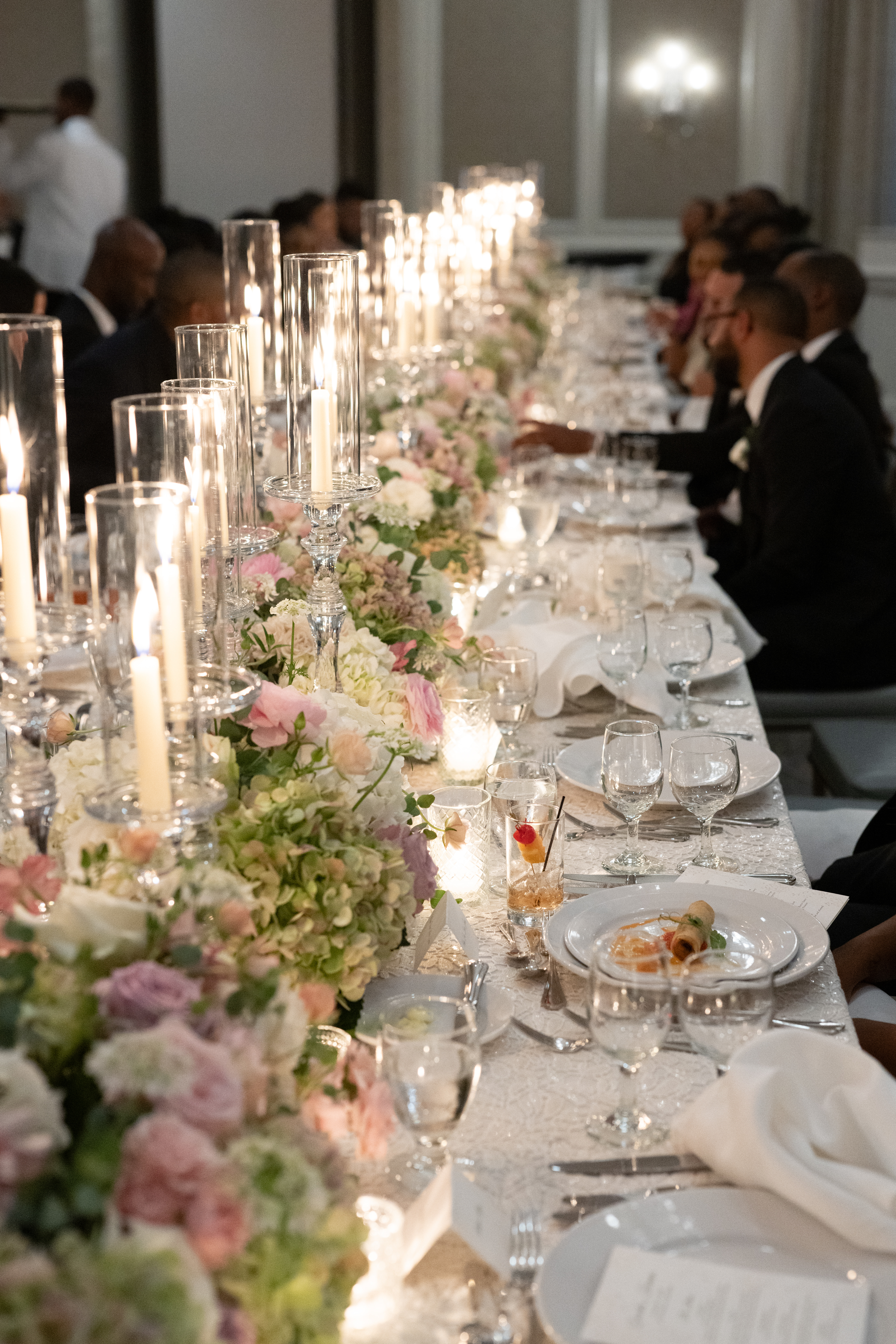 A formal dining table set with candles, flowers, and fine china.