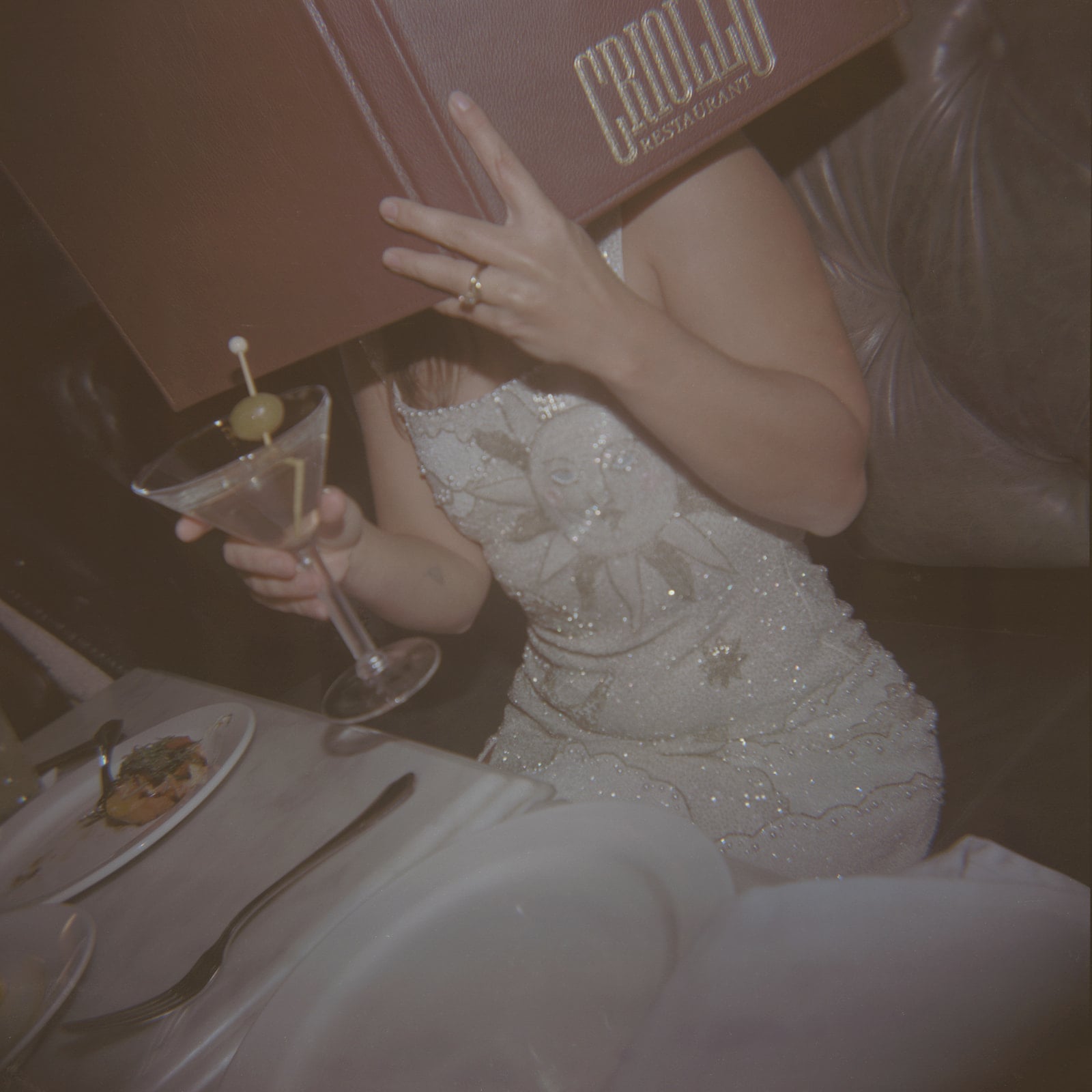 Dining guest with a martini, reading a Criollo Restaurant menu in New Orleans.