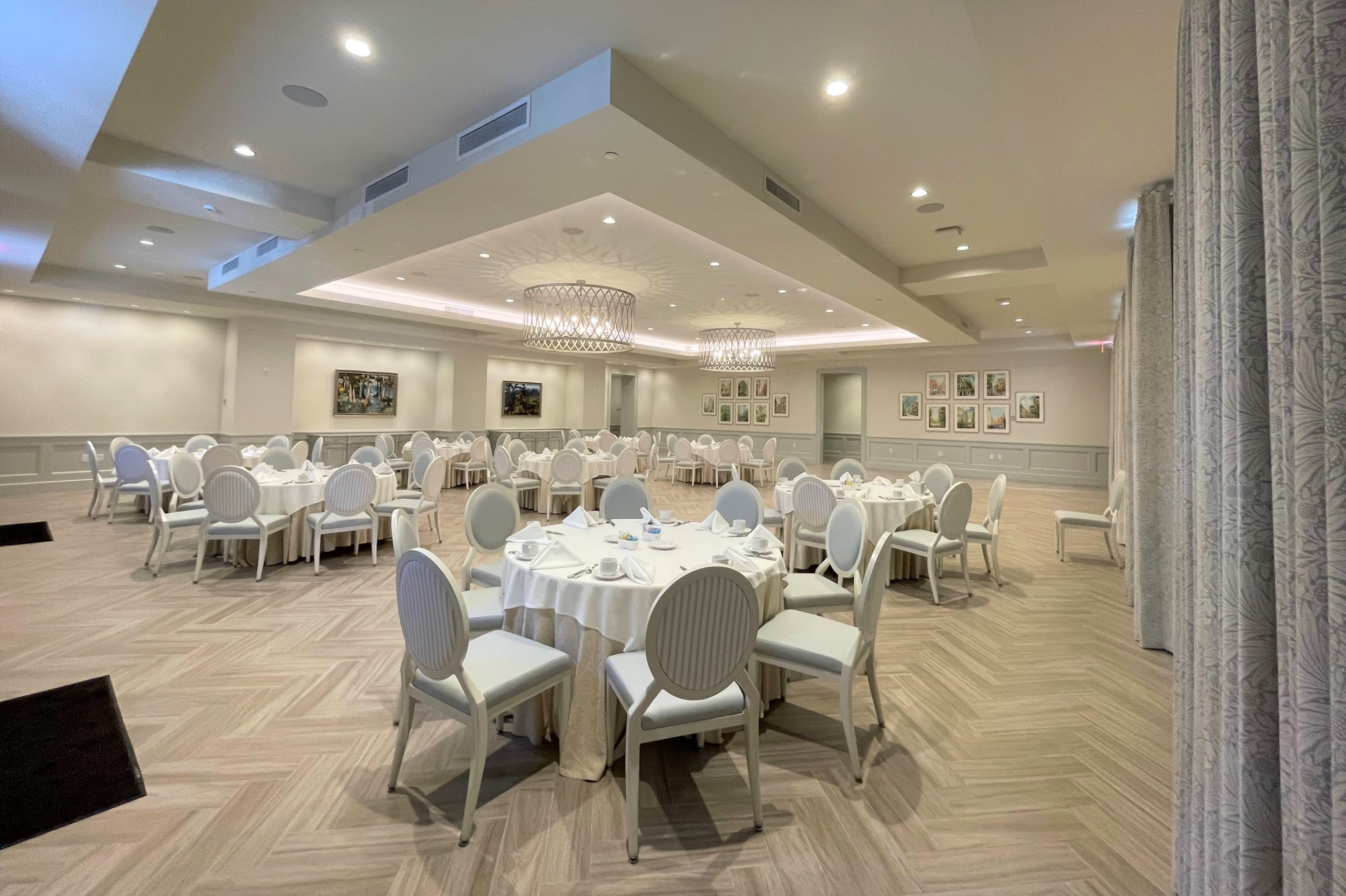 Spacious New Orleans ballroom set with white tables and chairs for a reception or banquet.