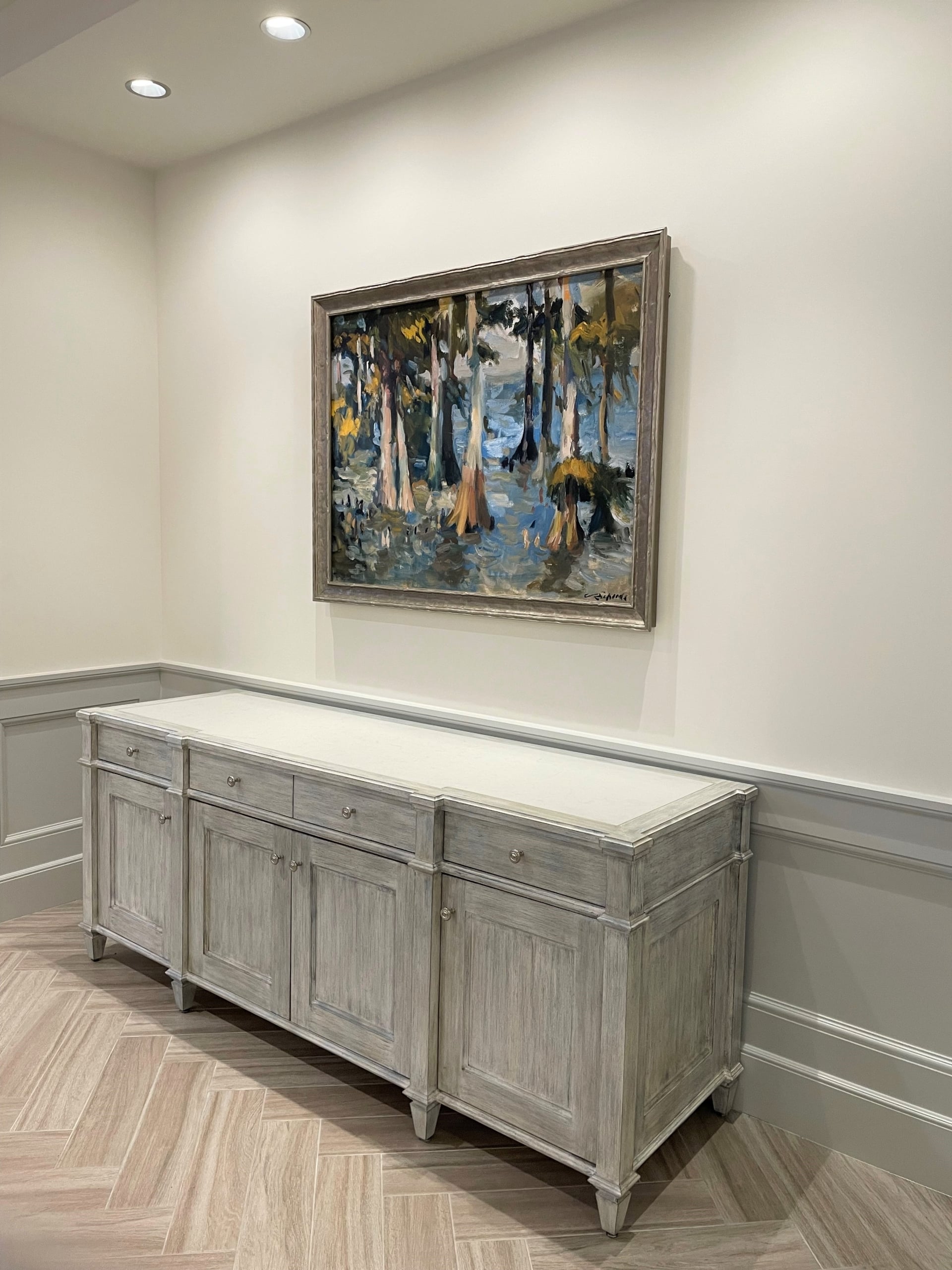 Painting of a cypress swamp above an elegant grey sideboard in a New Orleans hospitality suite.