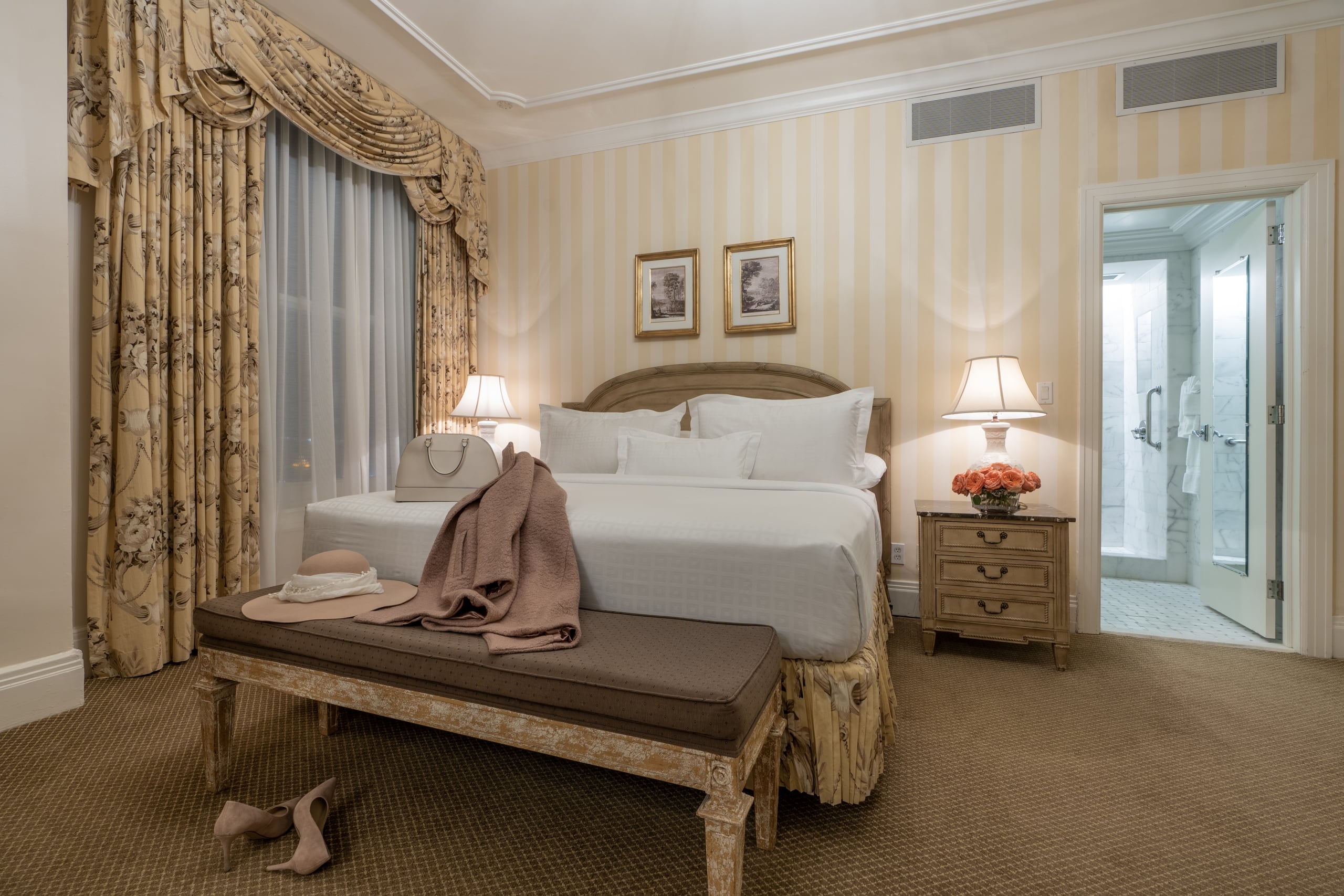 Luxurious hotel bedroom with a king bed, elegant decor, and en suite bathroom, ideal for a New Orleans stay.