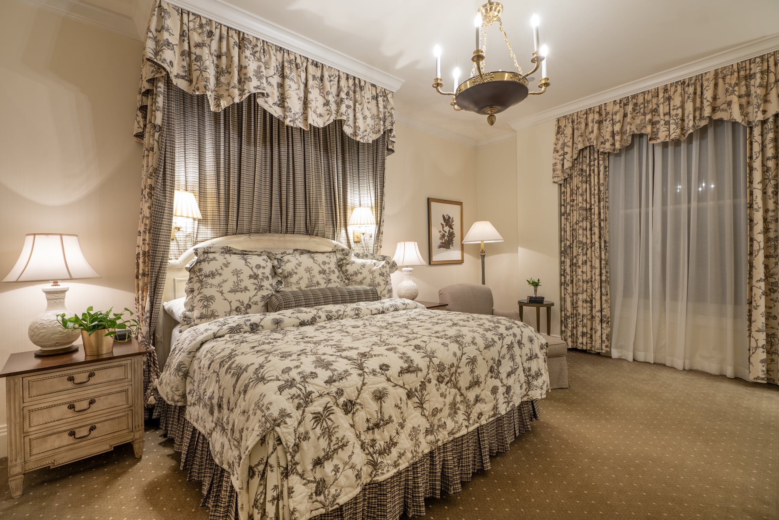 Luxurious New Orleans hotel room with a canopy bed, toile bedding, and elegant chandelier.