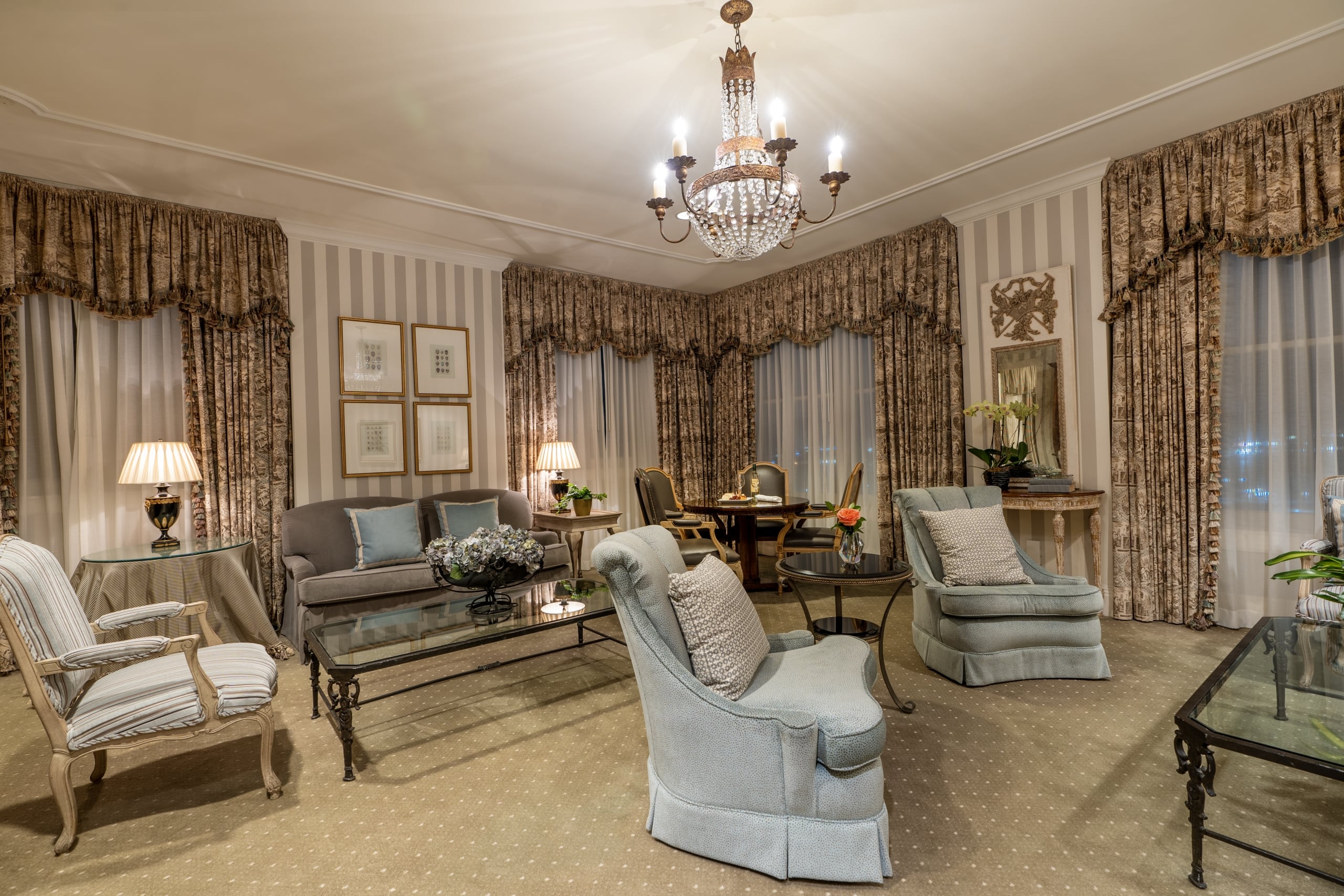 Luxurious New Orleans hotel suite with classic seating, ornate chandelier, and a cozy dining area.