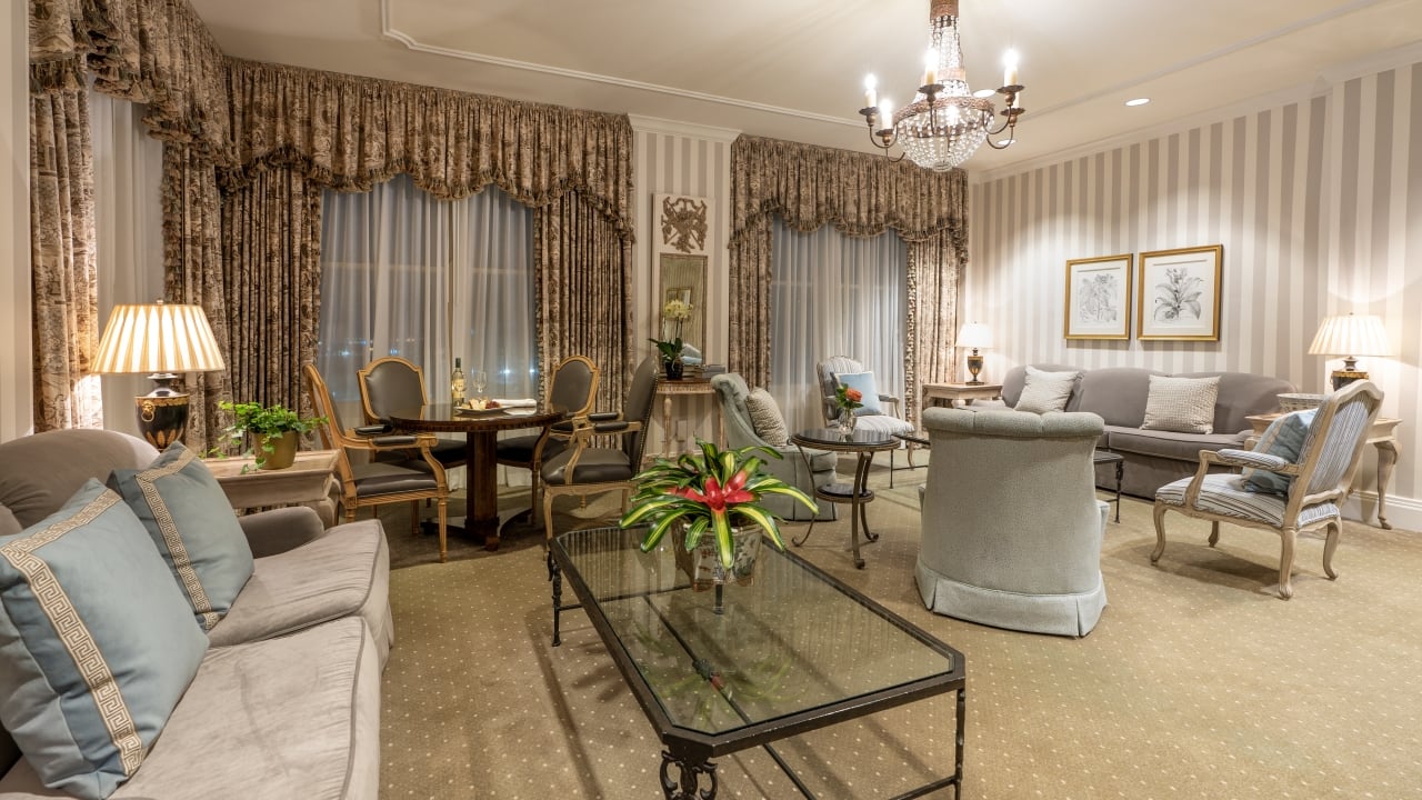 A wide view of a luxurious living room with a gray couch, chairs, and a glass coffee table.