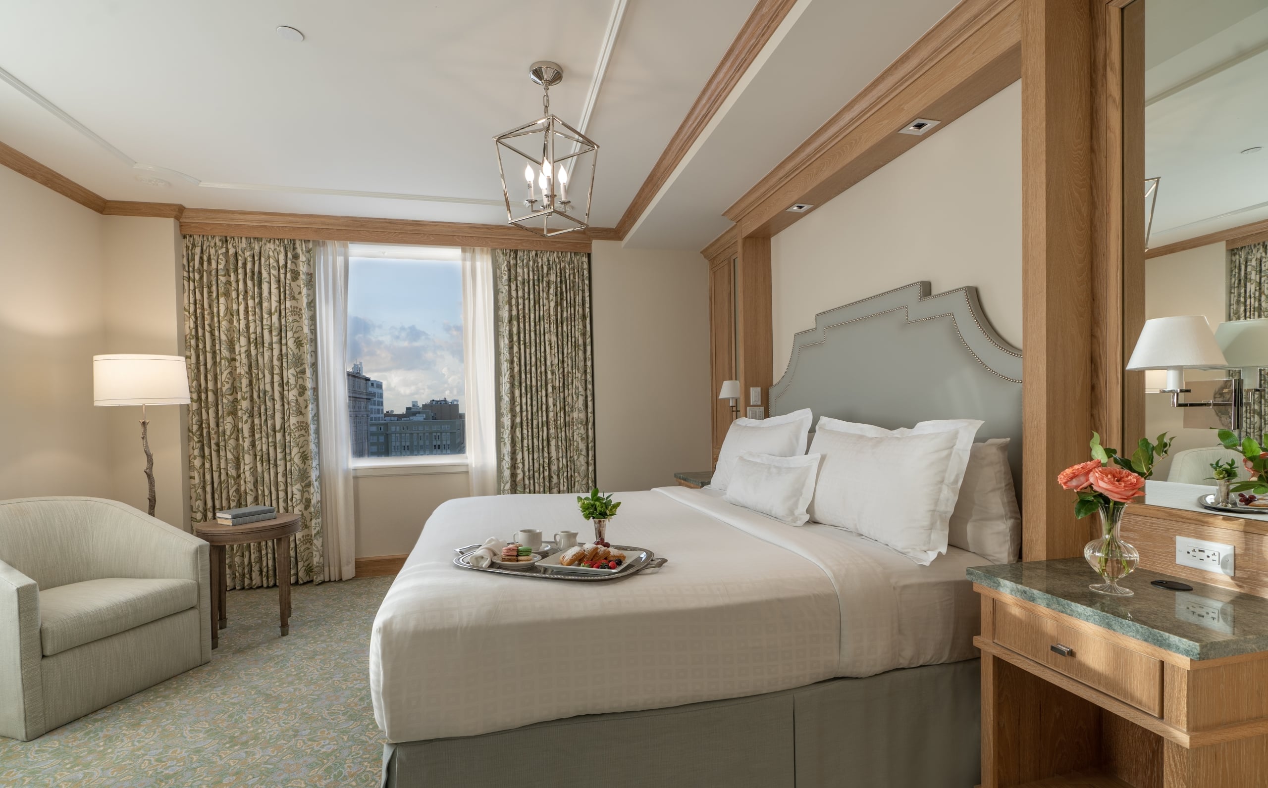 Luxurious New Orleans hotel room with king bed, breakfast, city view, and elegant decor.