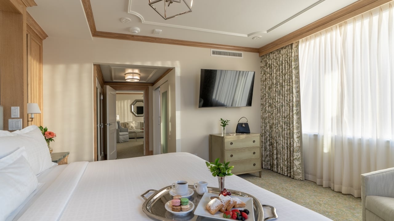 A hotel room with a bed, TV, window, and dresser.