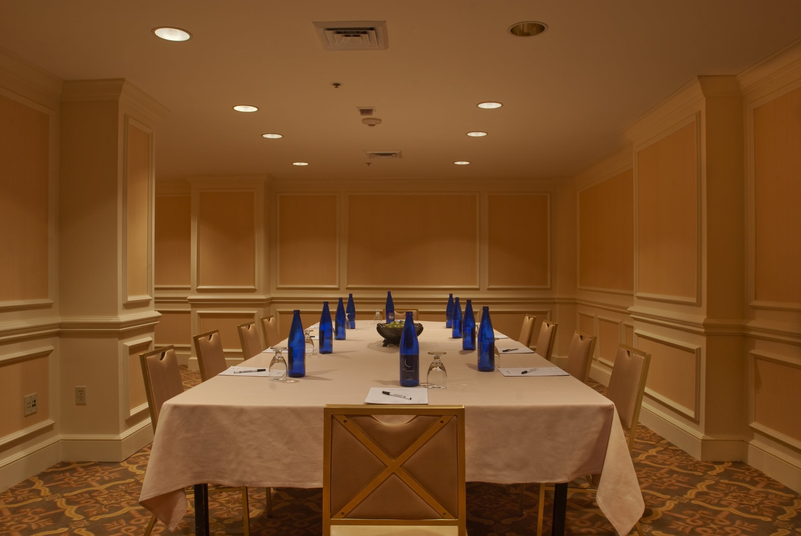 Elegant New Orleans hotel conference room set with a long table, chairs, and amenities.