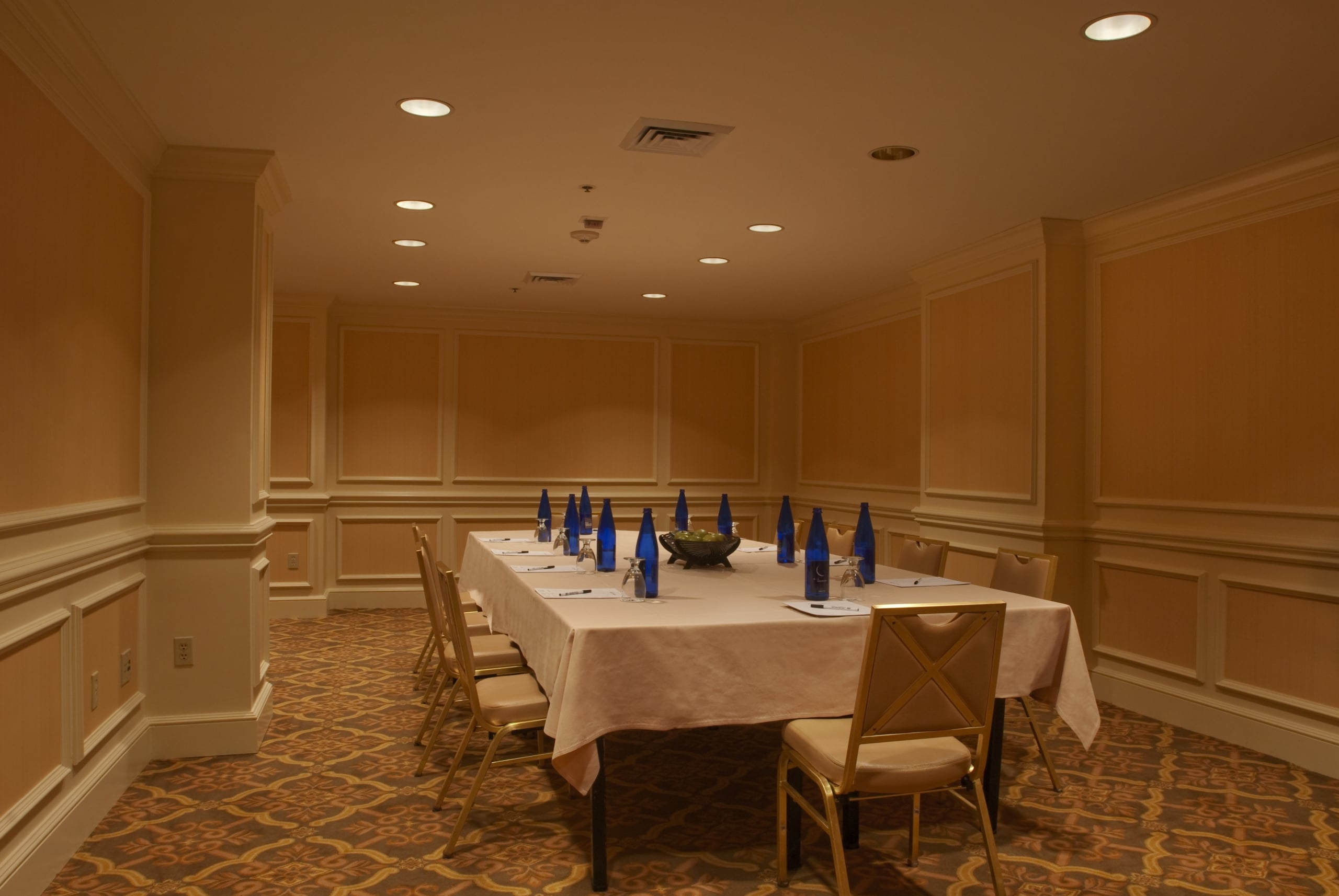 Elegant New Orleans hotel conference room set with a long table, chairs, and amenities.