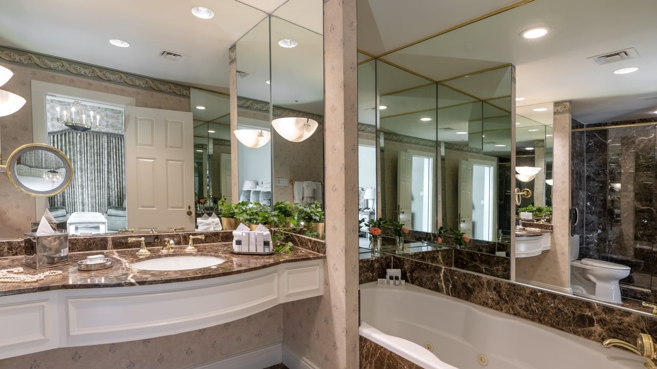 A luxurious bathroom with a marble countertop, gold fixtures, and a large mirror.
