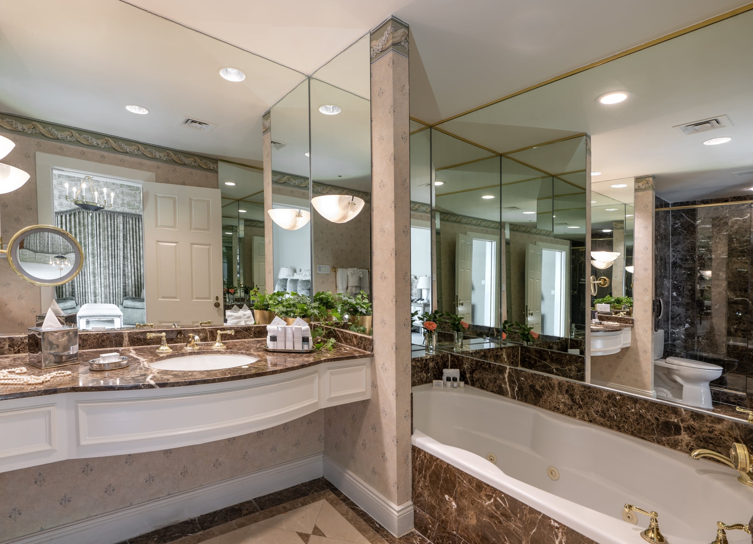 Spacious luxury bathroom in New Orleans hotel with marble vanity, gold fixtures, and jetted tub.