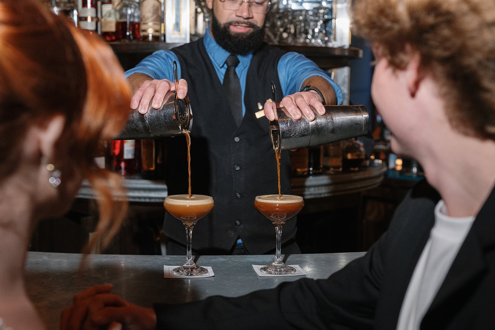 Bartender pouring two espresso martinis for guests at a New Orleans bar.