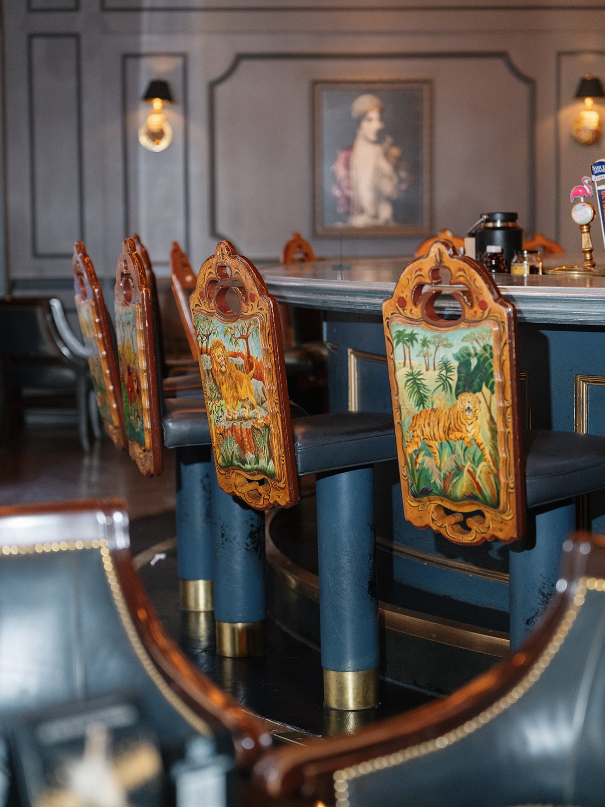 Stylish New Orleans hotel bar with unique bar stools featuring hand-painted lion and tiger jungle scenes.