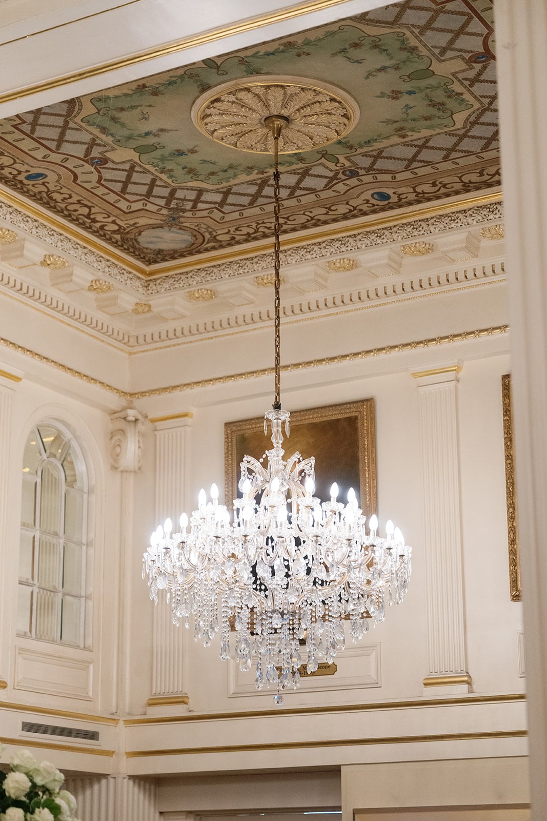Grand crystal chandelier and painted ceiling in a historic New Orleans hotel.