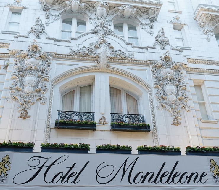 The ornate white facade of a building with a sign reading 'Hotel Monteleone'