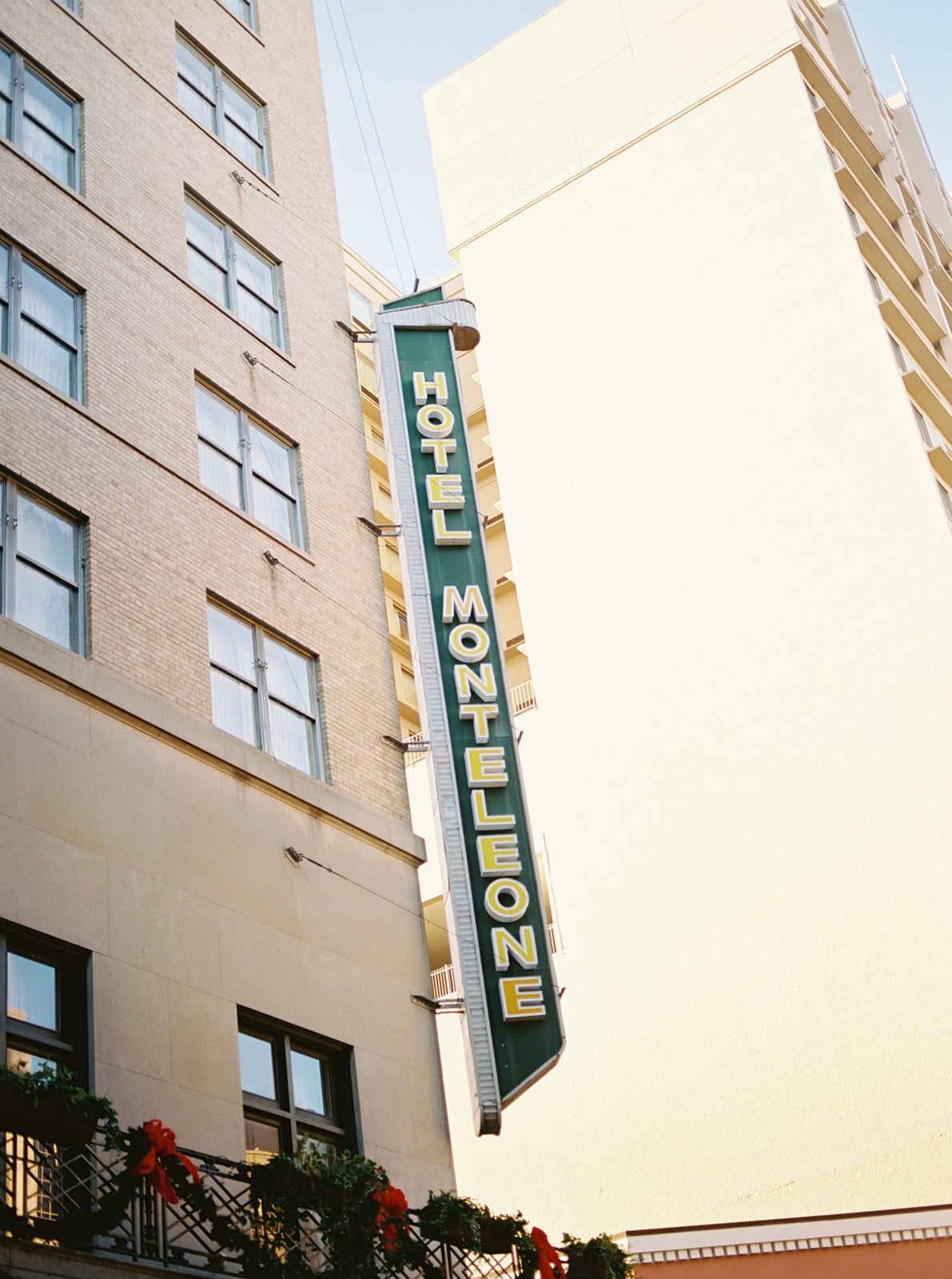 Iconic Hotel Monteleone vertical sign in New Orleans, with festive holiday decor on a balcony.