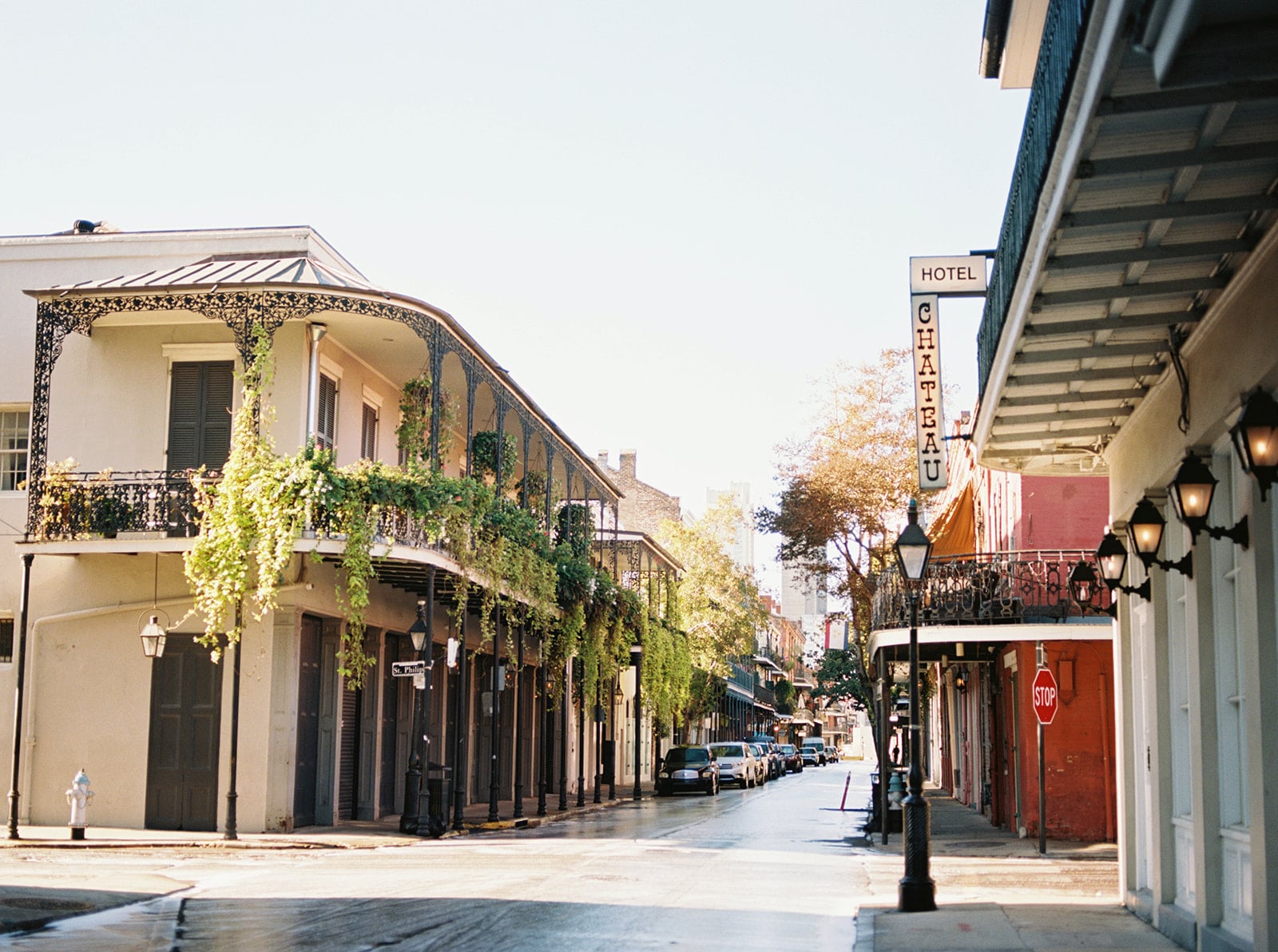 Street view of Hotel Chateau on St. Philip Street in New Orleans' French Quarter with iron balconies and lush plants.