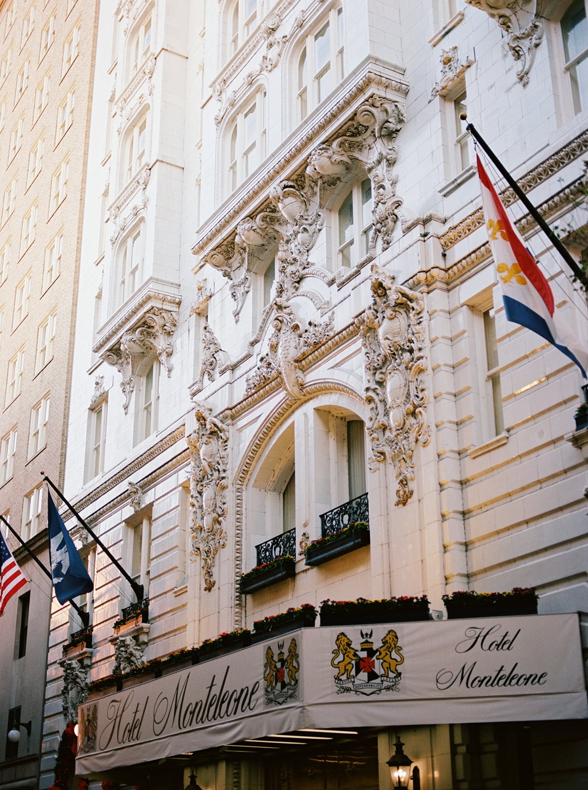 Historic Hotel Monteleone in New Orleans, featuring ornate white facade, flags, and elegant details.