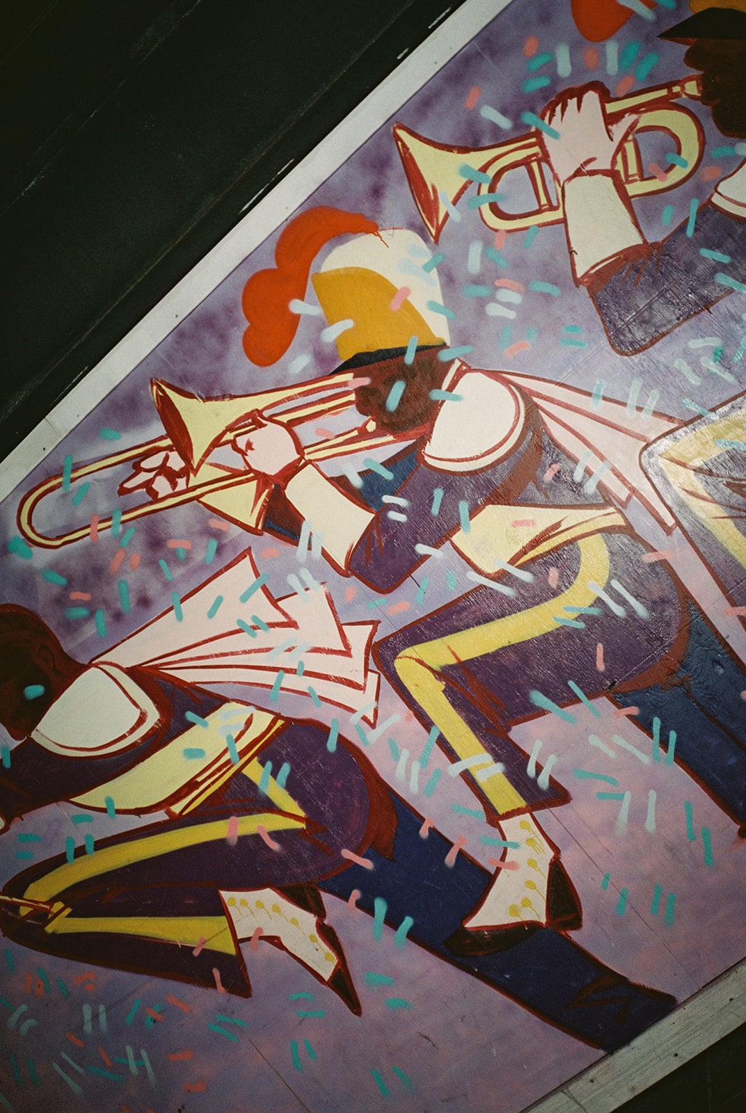 New Orleans mural of a lively brass band playing trumpets and trombones amidst colorful confetti.