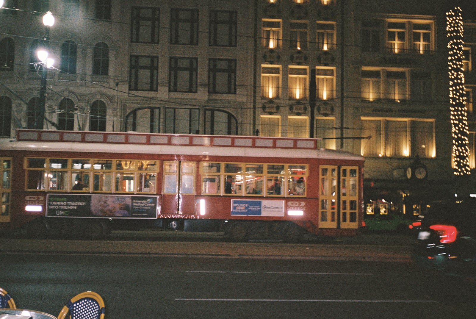 Historic New Orleans streetcar at night on a city street, with illuminated buildings in the background.