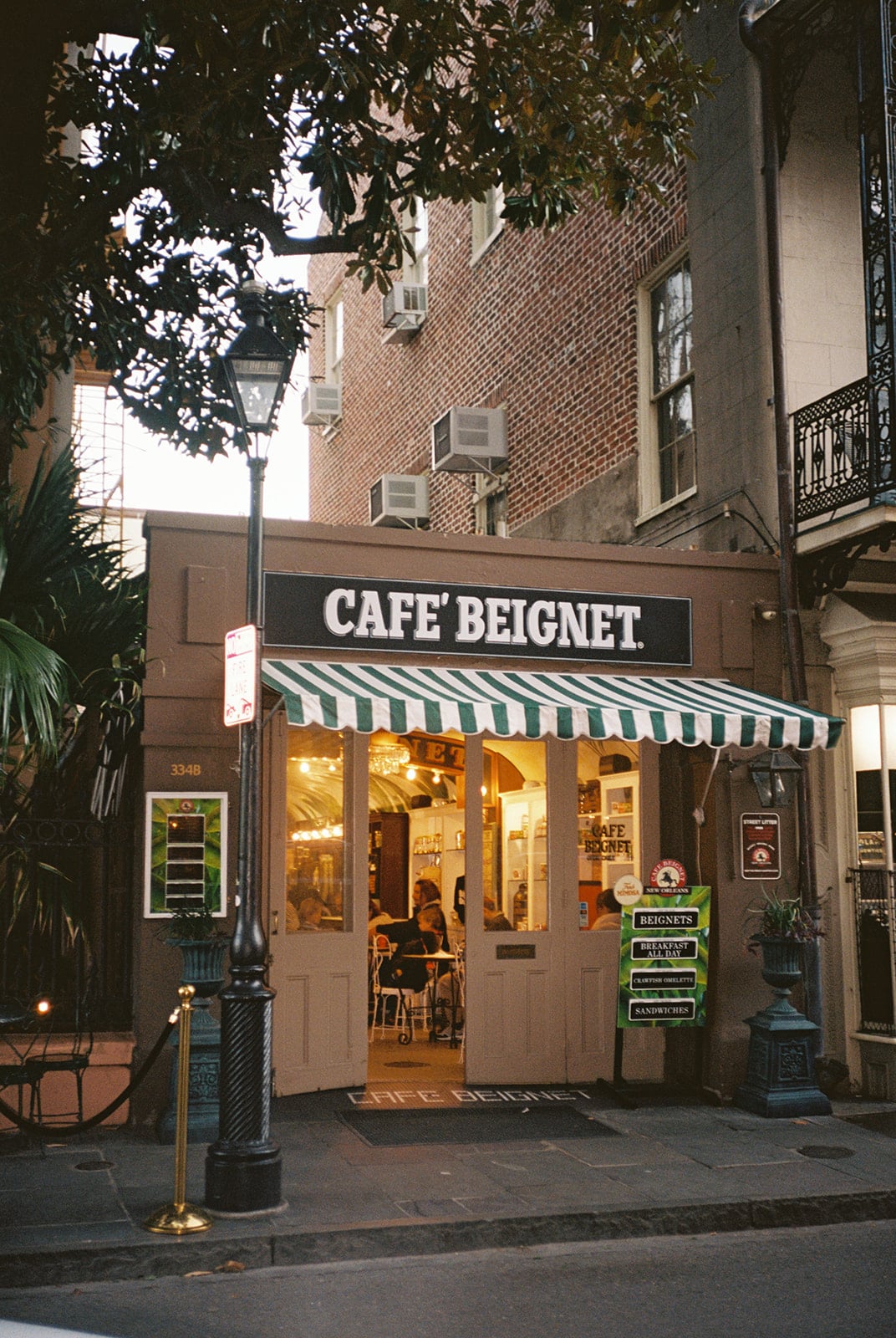 Cafe Beignet in New Orleans, serving famous beignets, with a green striped awning and open doors.