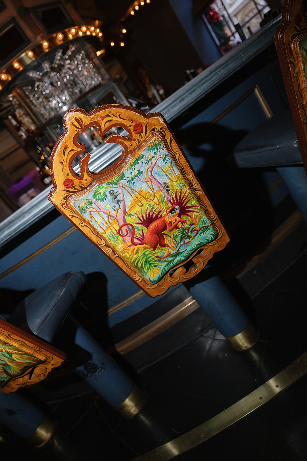 Vibrant, ornate bar stool in a New Orleans lounge, featuring a hand painted tropical scene with red monkeys.