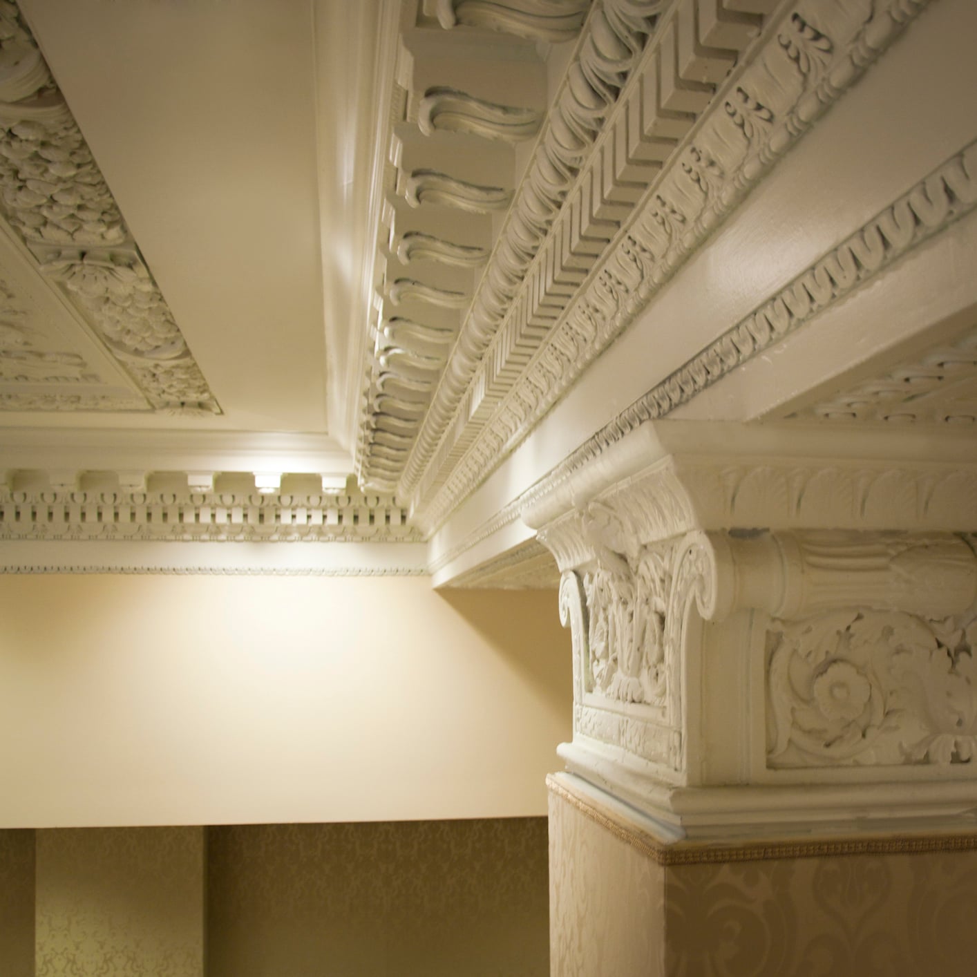 Intricate white plaster molding and column details in a New Orleans luxury hotel.
