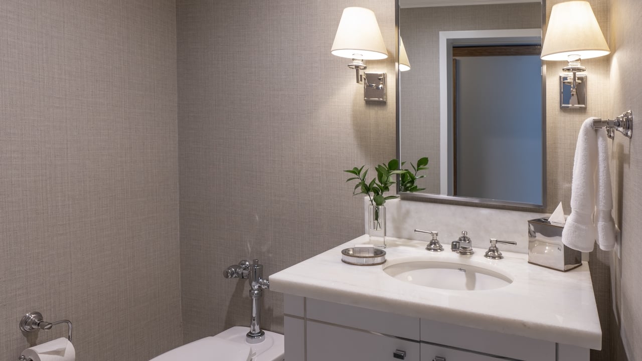 A clean bathroom with a marble countertop, silver fixtures, and white towels.