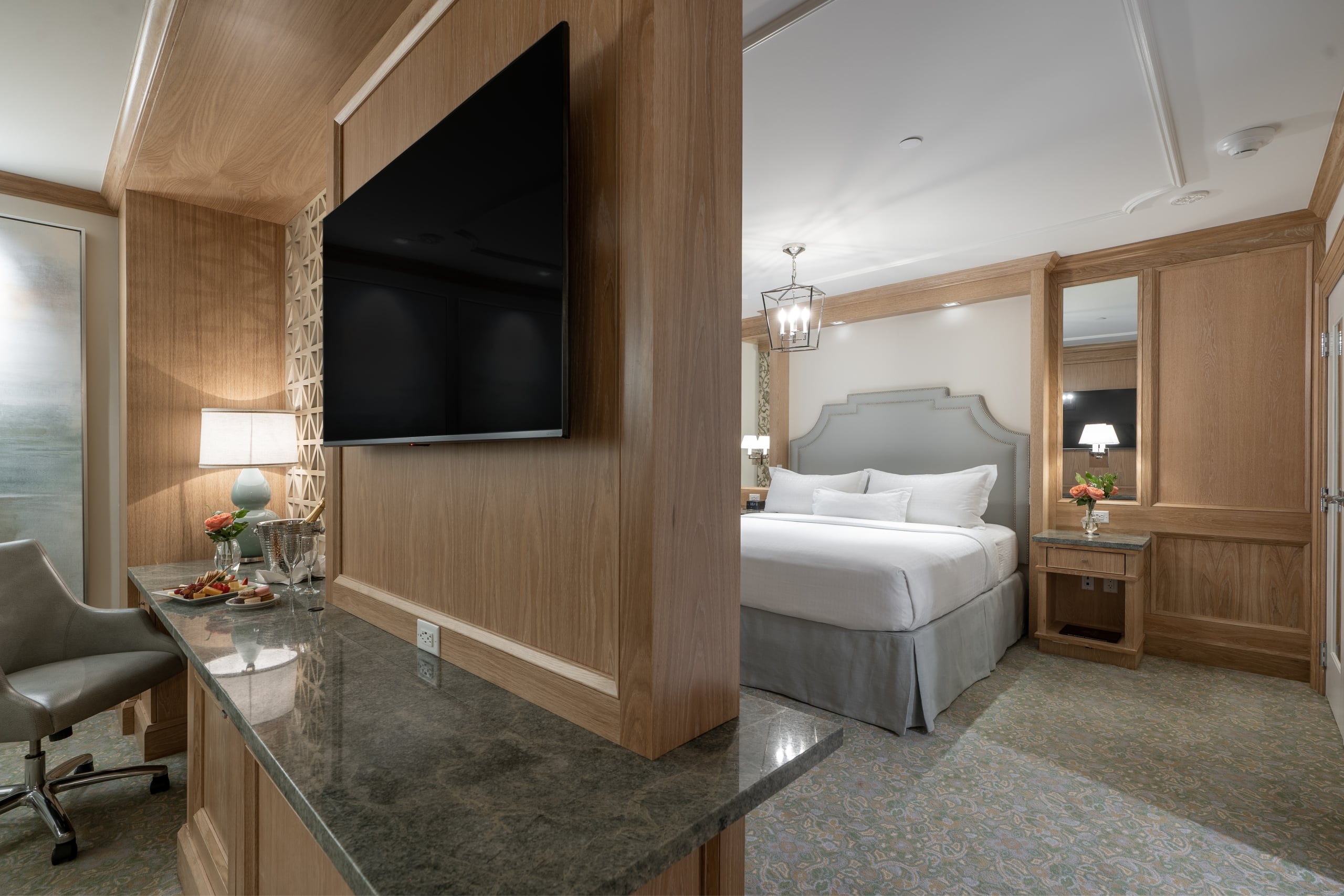 Elegant hotel suite in New Orleans with a bedroom, desk, TV, and welcome amenities.